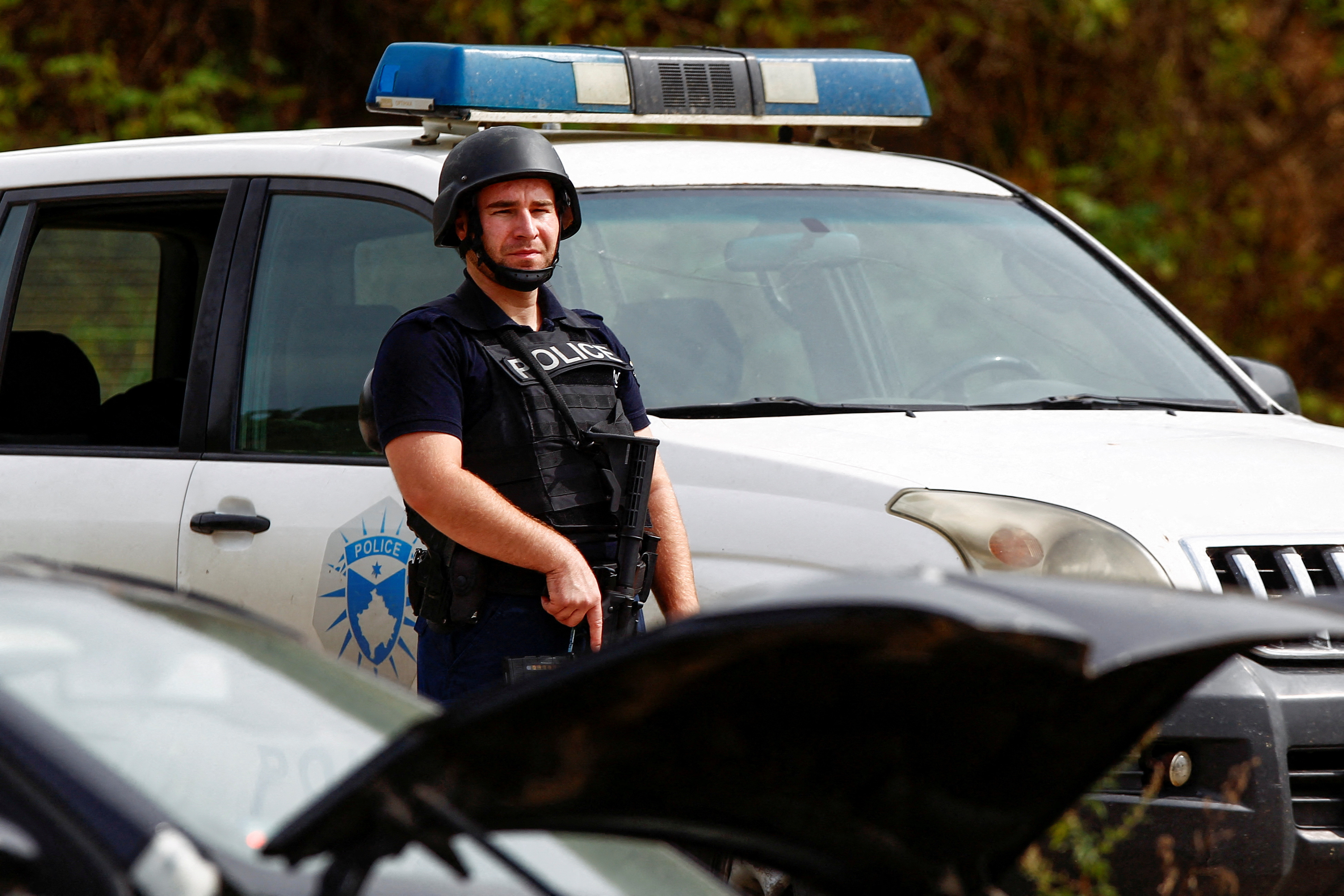 A police officer stands guard in the aftermath of a shooting, near the village of Zvecan, Kosovo [Ognen Teofilovski/Reuters]