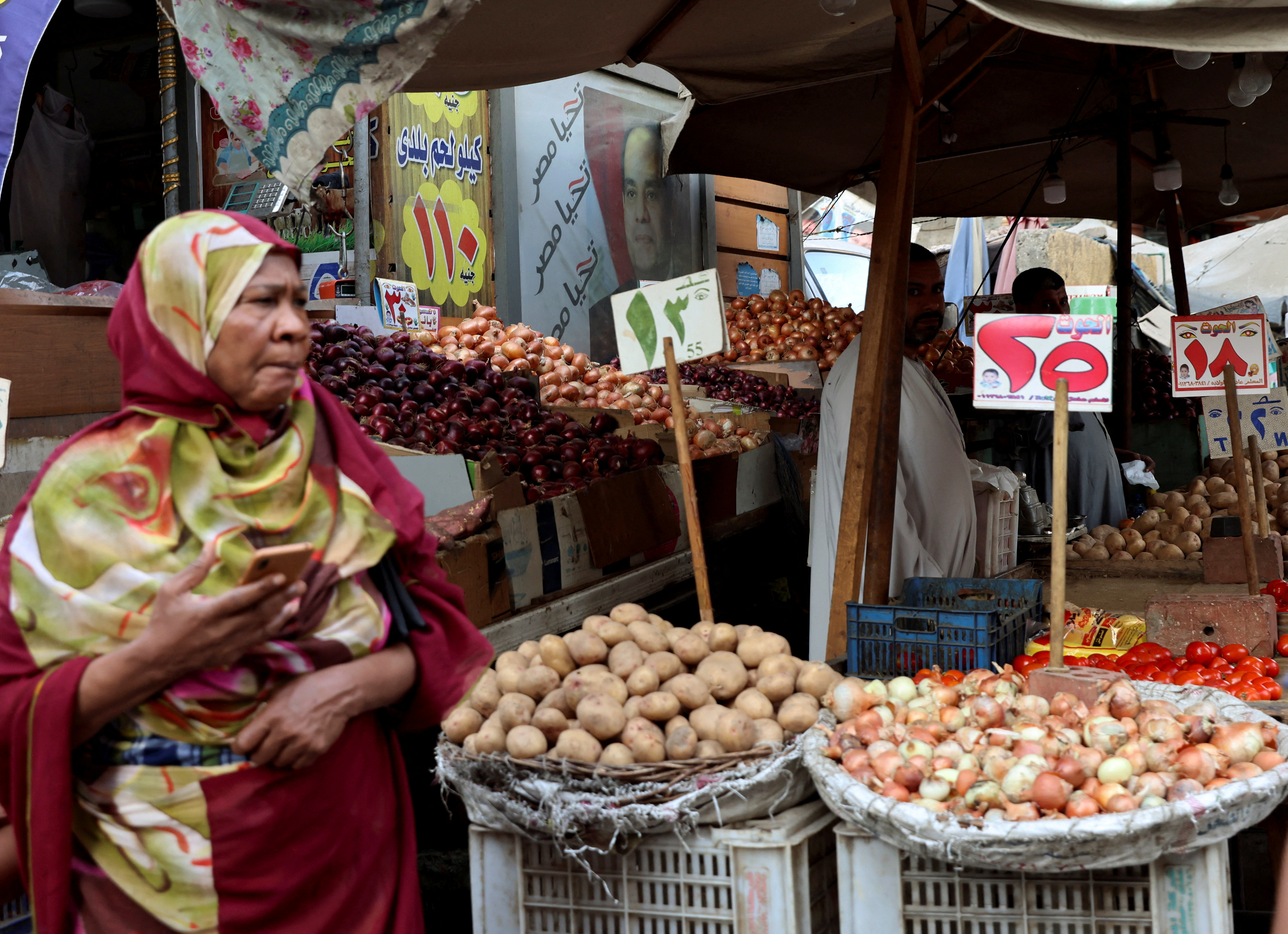 A vendor waits for customers besides a banner with an image of the Egyptian President Abdel Fattah el-Sisi