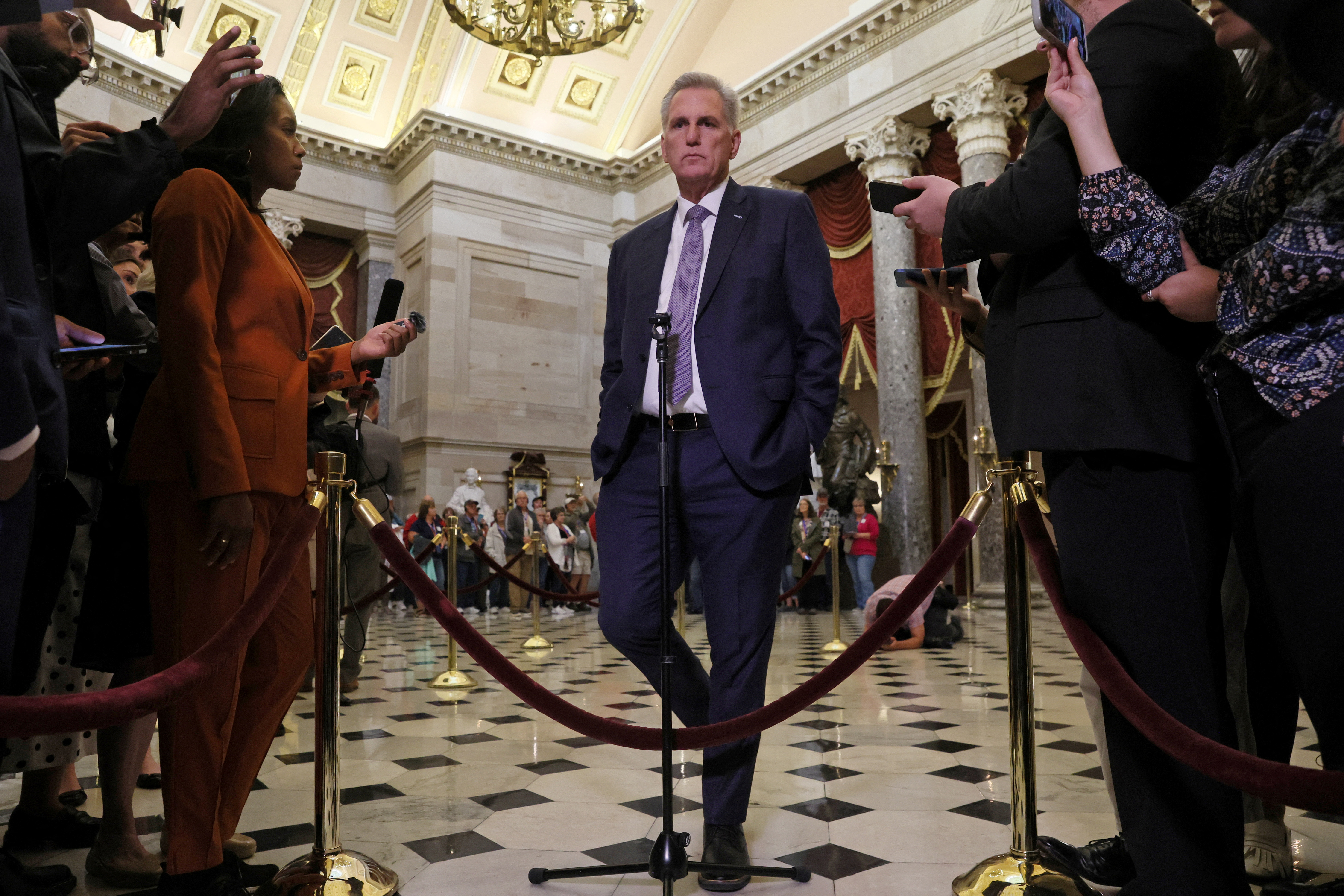 U.S. House Speaker Kevin McCarthy speaks to members of the media as the deadline to avert a government shutdown approaches on Capitol Hill in Washington, U.S., September 26, 2023. Under a domed, ornate ceiling, he stands behind velvet ropes, as reporters hold out their recording devices and ask questions.