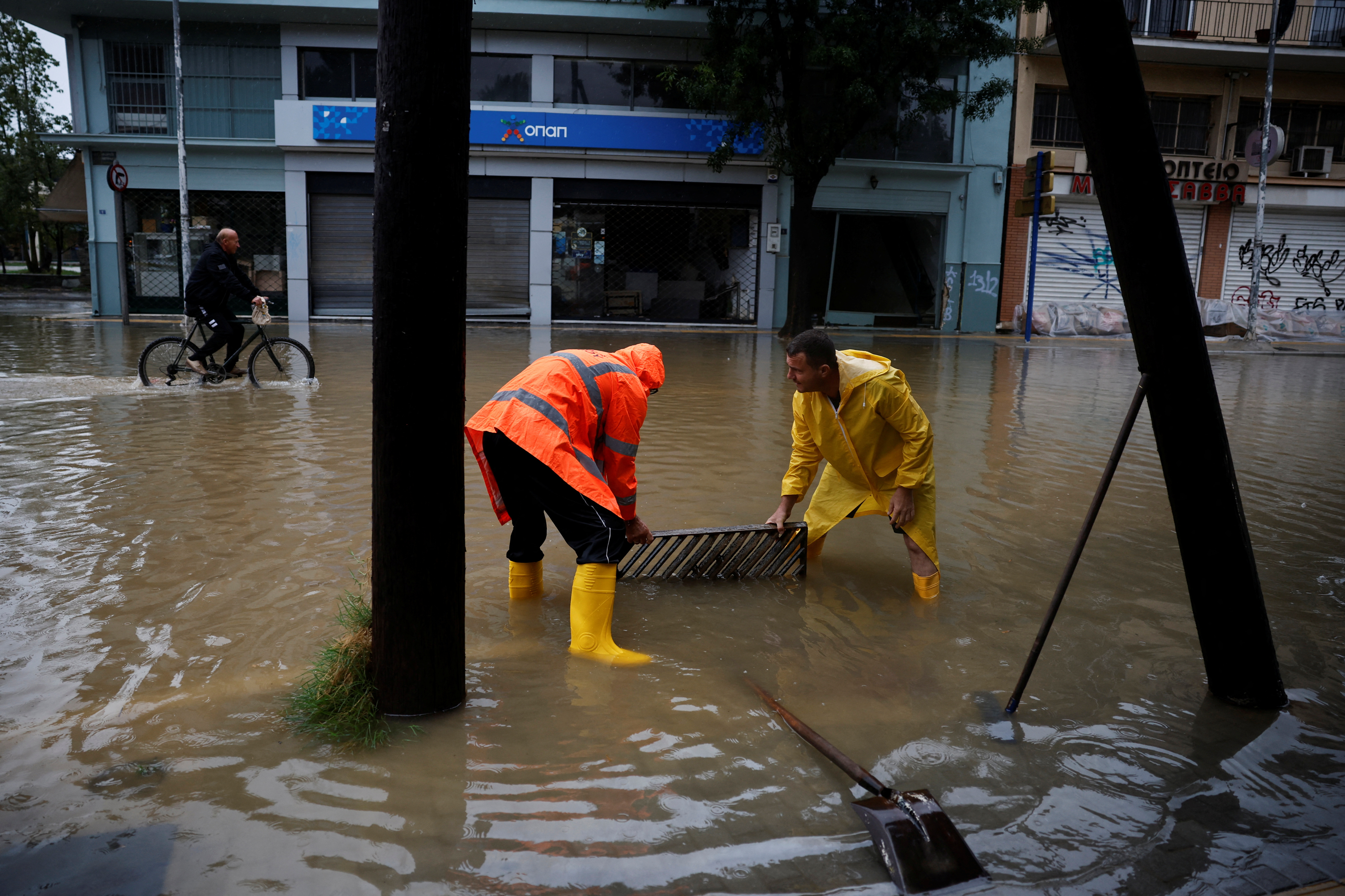 Workers unblock drainage at a flooded central street in the city of Volos 