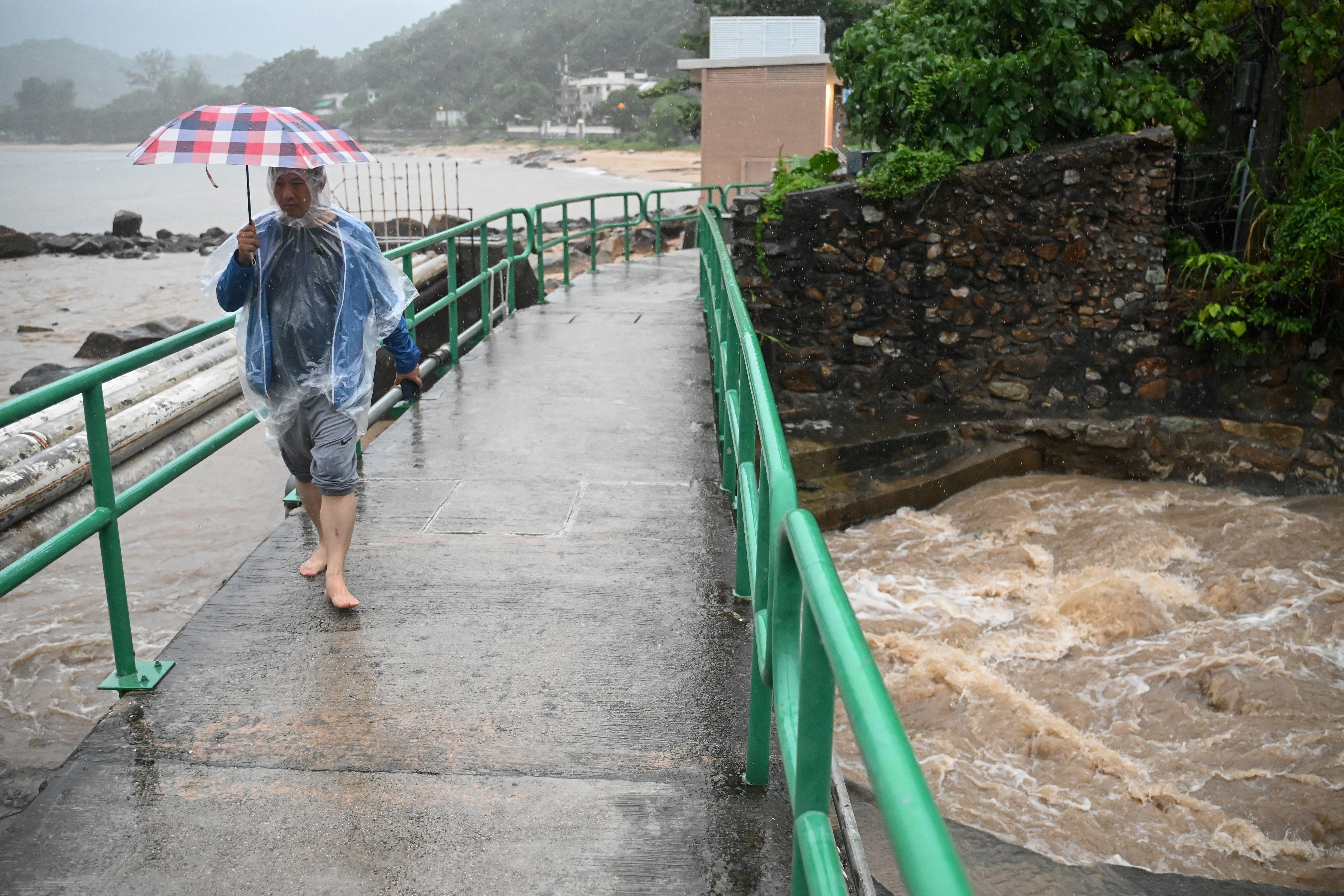 A man walks on a bridge over a swollen river on Lantau Island in Hong Kong