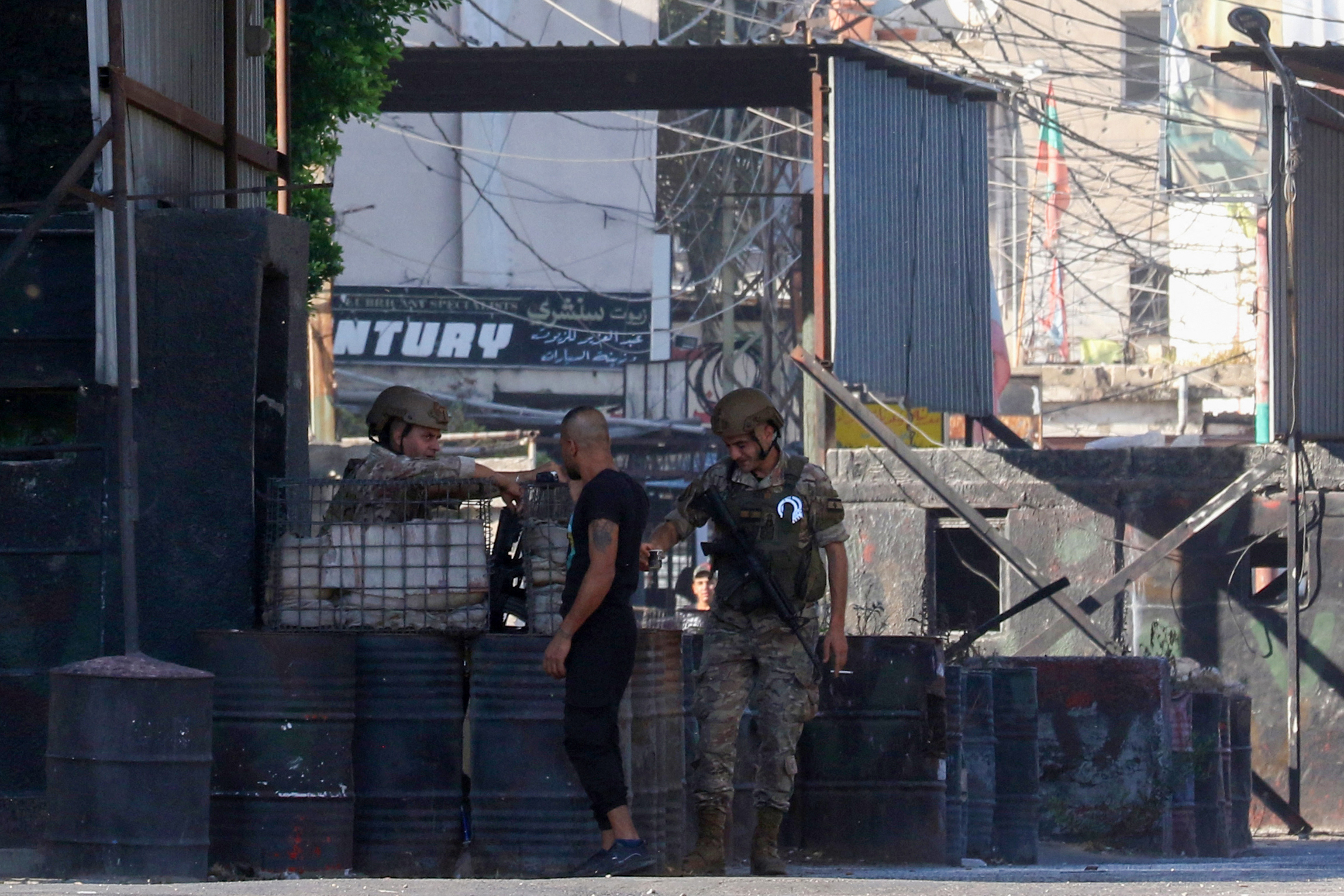 A man speaks with Lebanese soldiers as they stand guard at one of the entrances to the Ain el-Helweh camp for Palestinian refugees,