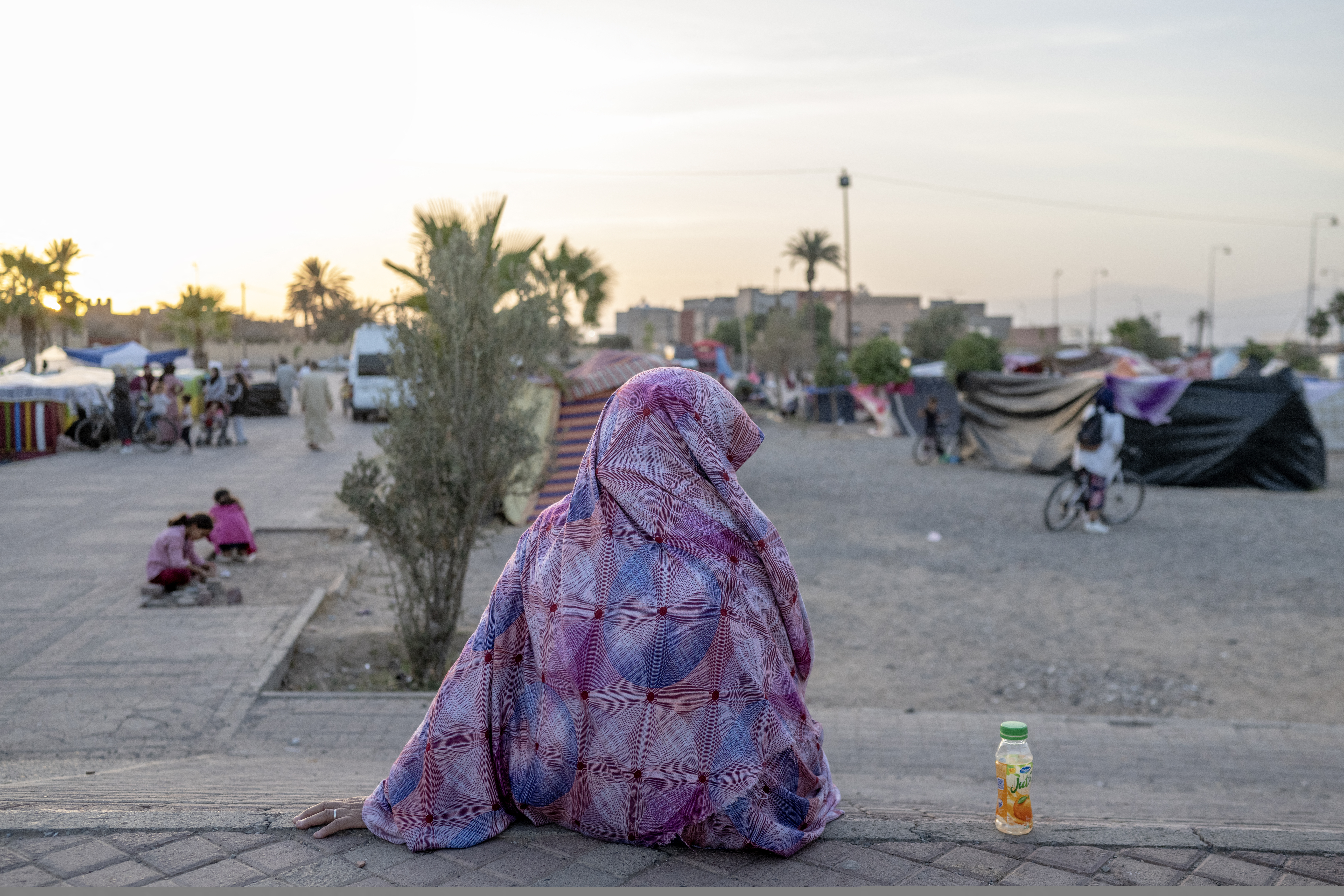 A displaced woman sits next to makeshift tents