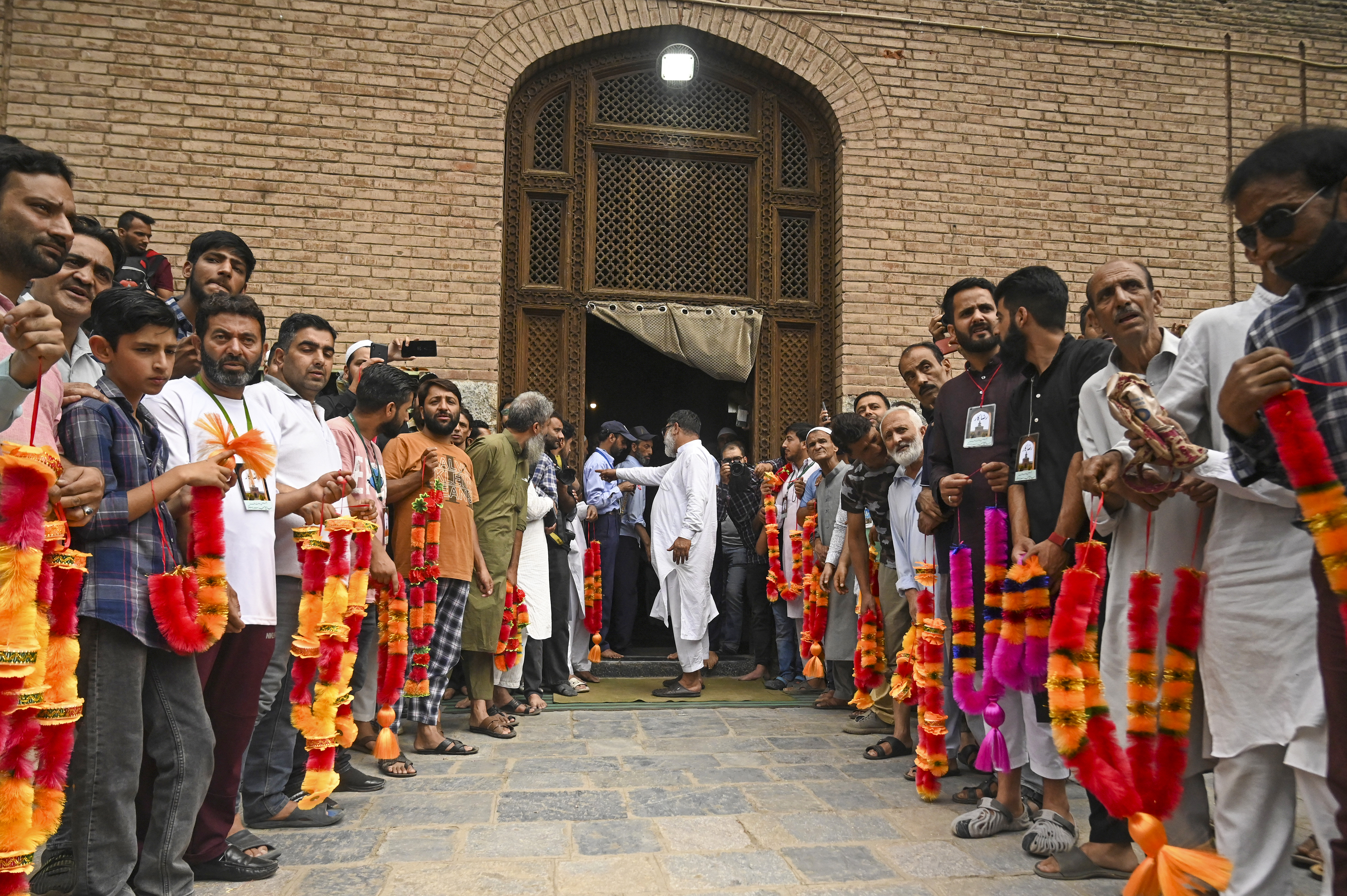 People wait with garlands as senior separatist leader Mirwaiz Umar Farooq