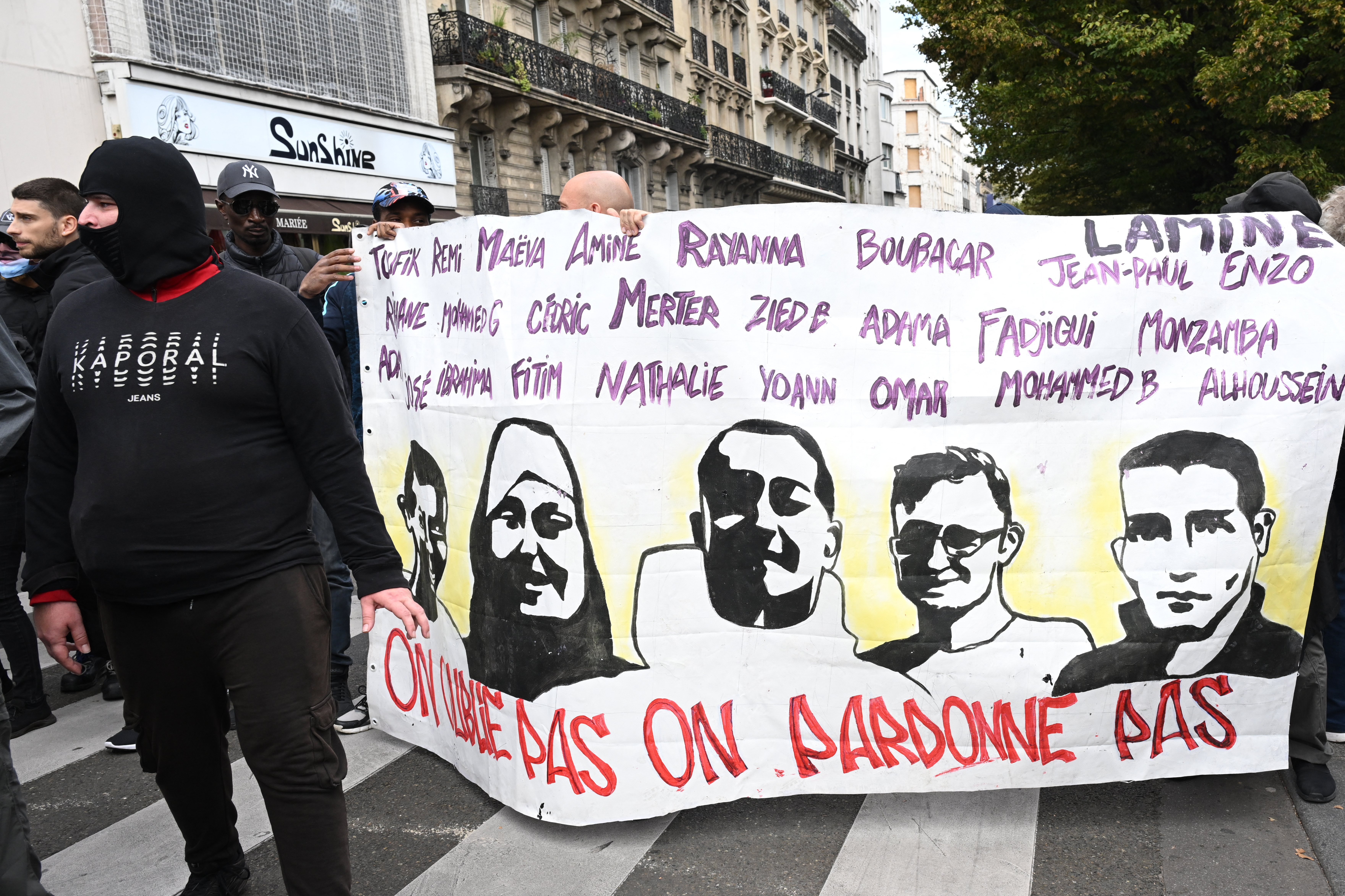 Protestors hold a banner bearing portraits of victims of alleged French police violence with a slogan which reads "We don't forget, we don't forgive" during a "united march" against police brutality called by NGOs, unions and parties, in Paris