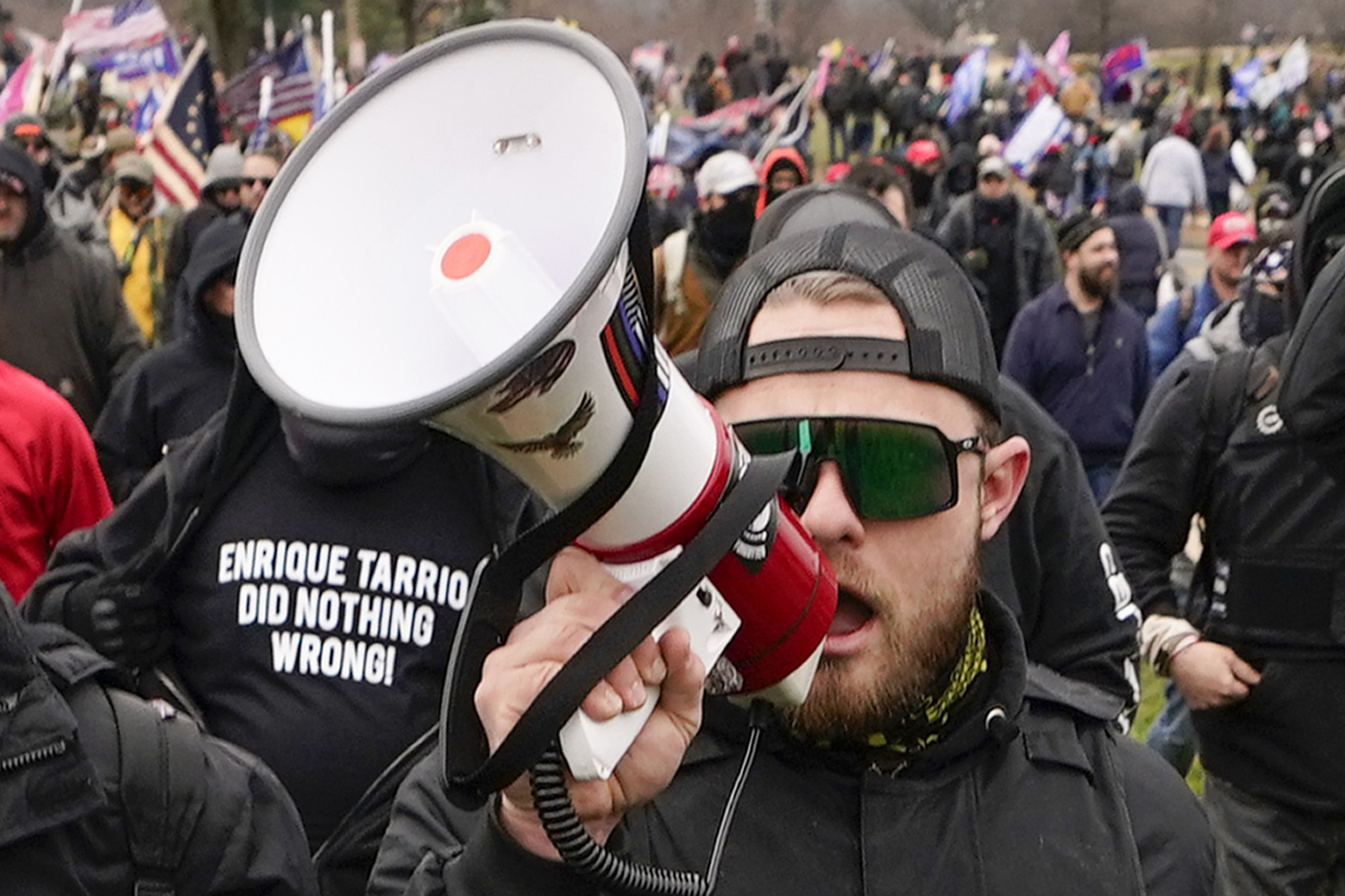 Proud Boy member Ethan Nordean walks toward the U.S. Capitol in Washington, in support of President Donald Trump on Jan. 6, 2021. He wears a backwards baseball cap and speaks through a bullhorn.