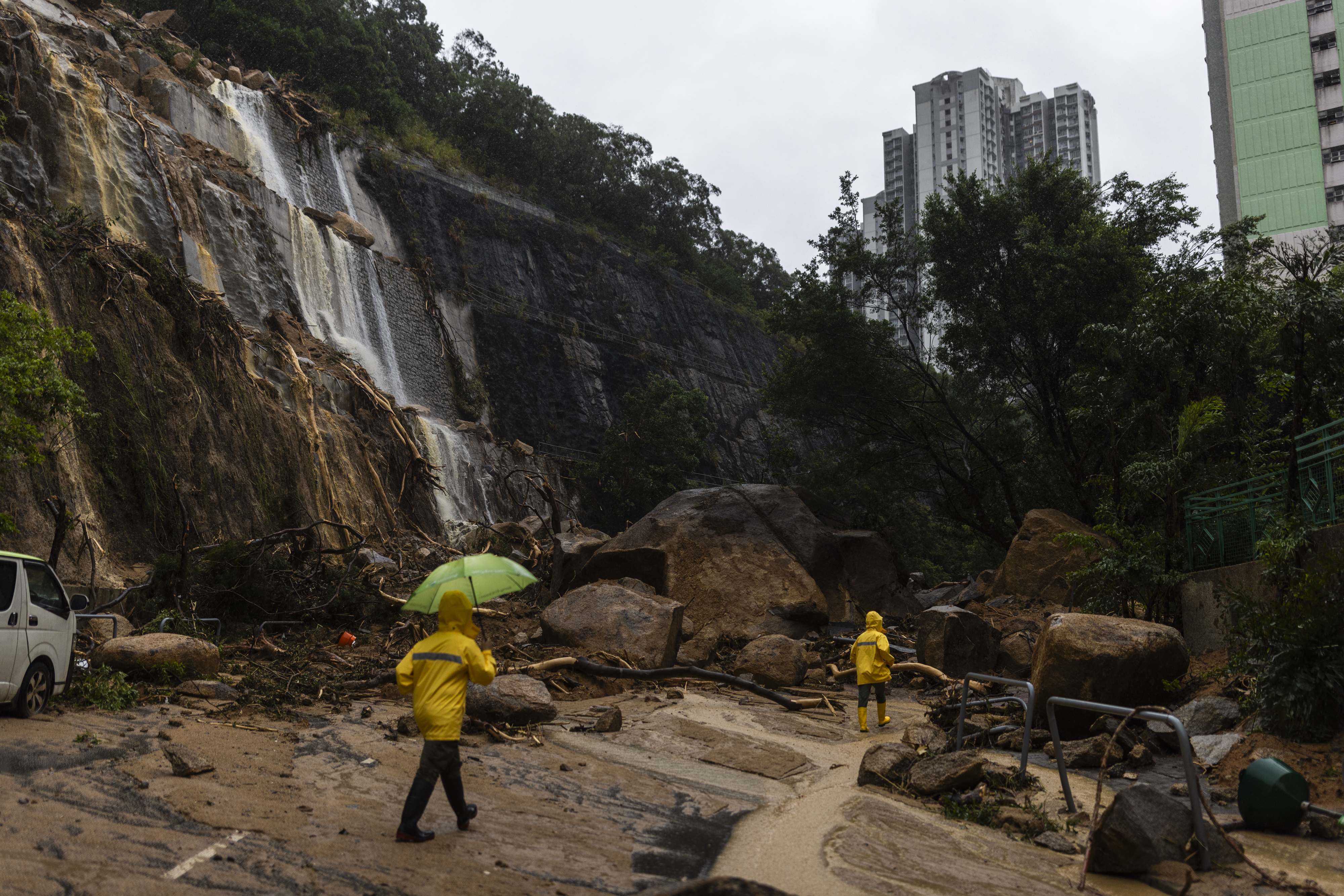 Workers walk through a landslide following heavy rainstorms in Hong Kong
