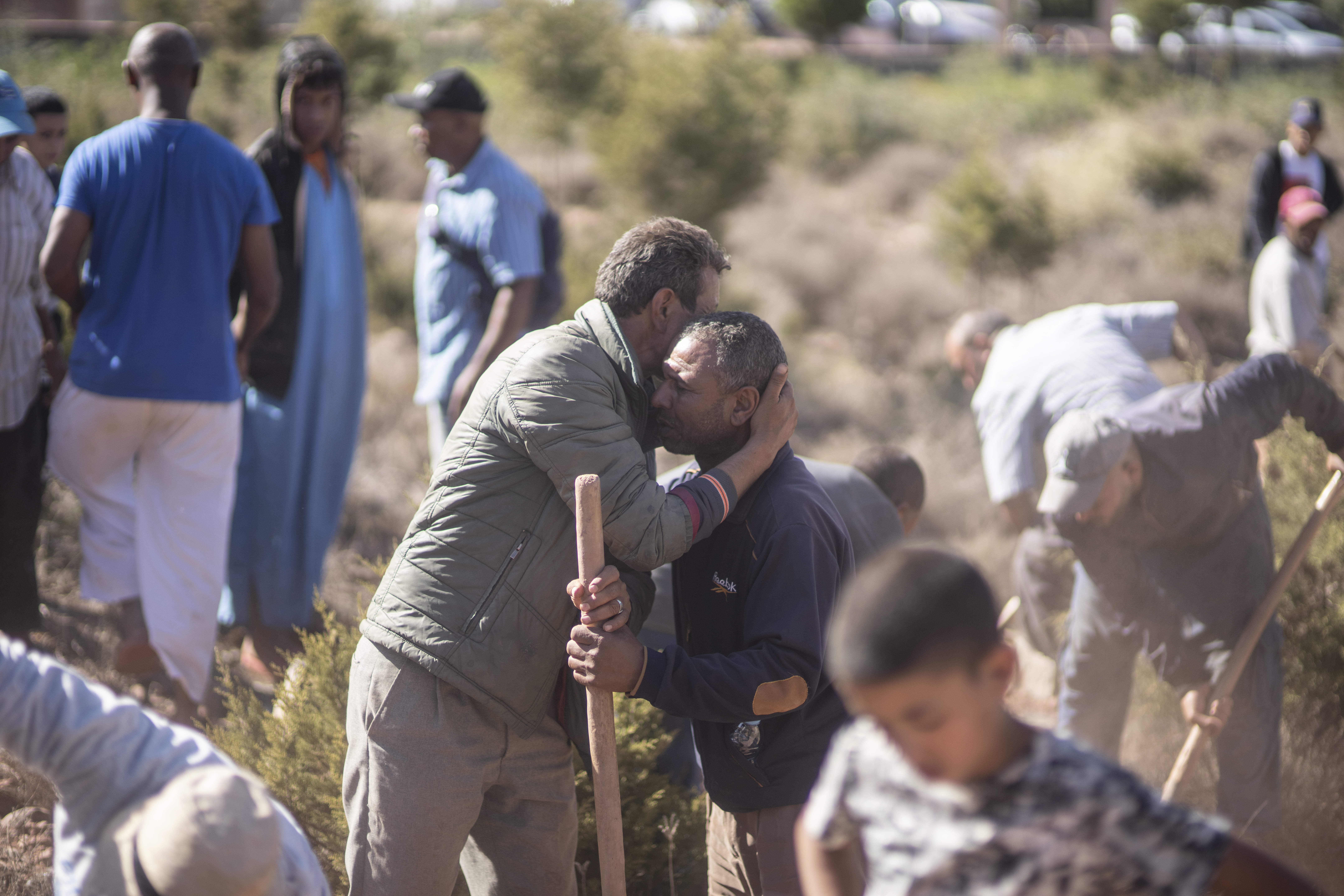People comfort each other while digging graves for victims of the earthquake near Marrakesh