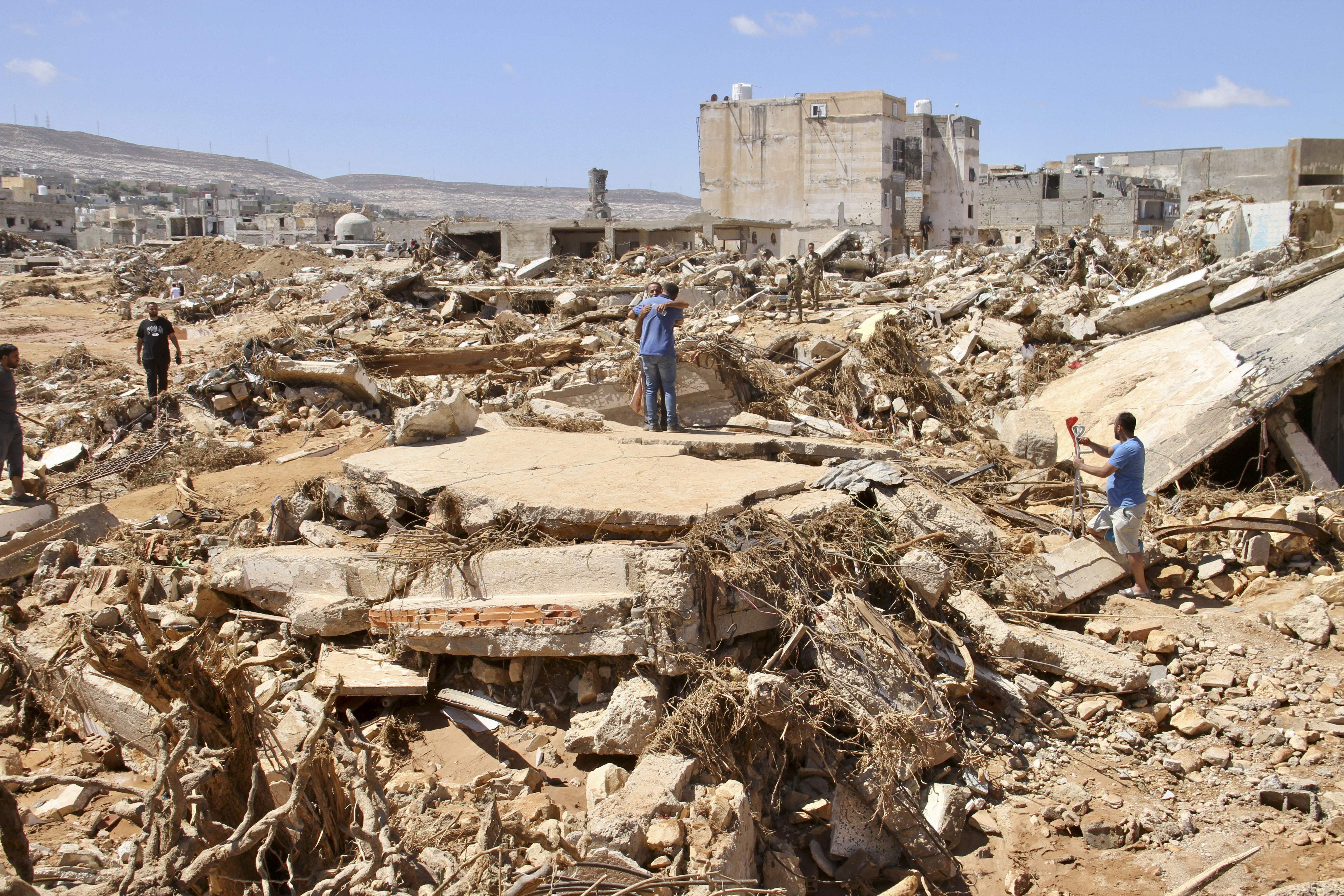 Two men hug as people look for survivors in the flooded city of Derna, Libya