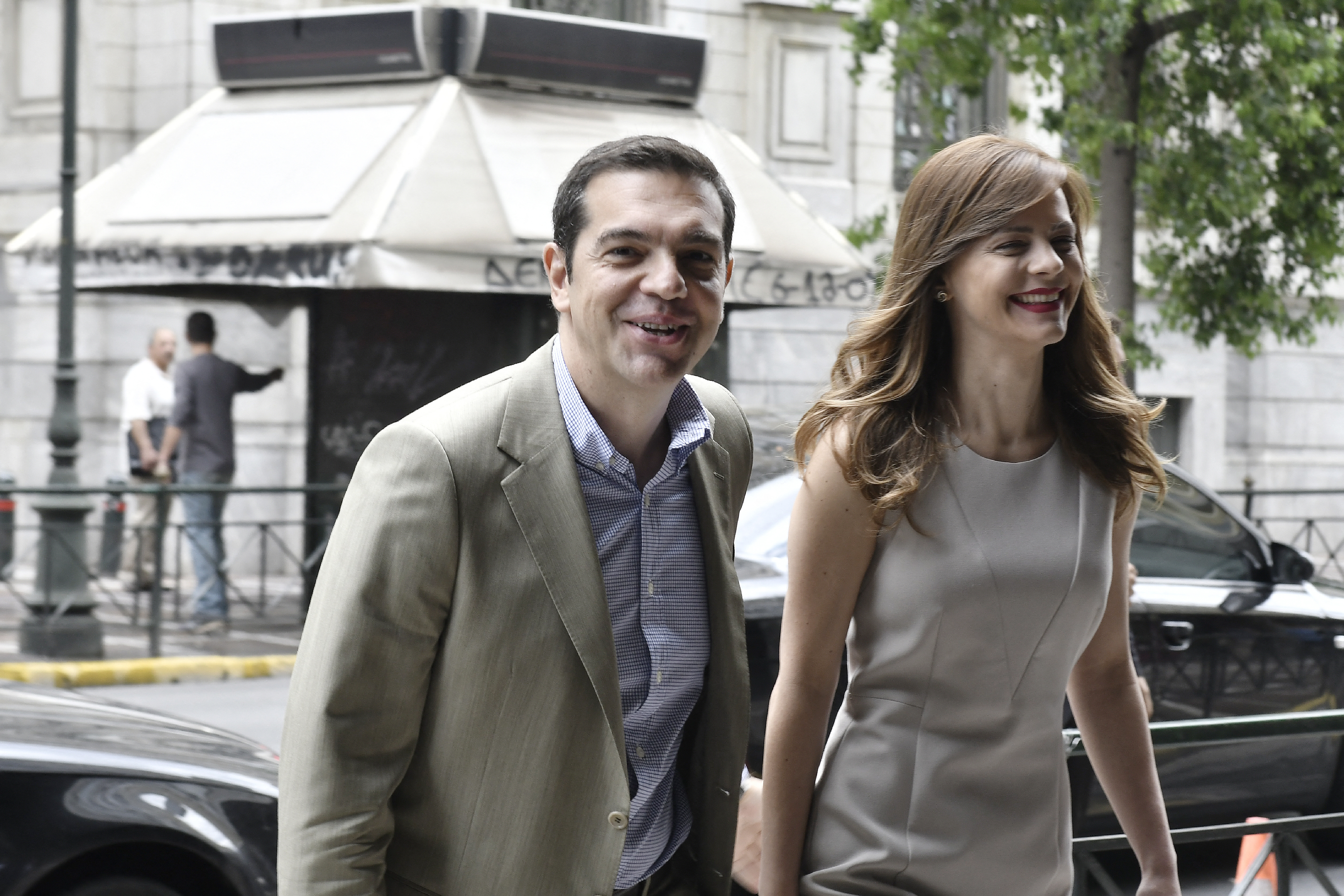 Greek prime minister Alexis Tsipras (L) smiles, while he arrives for his meeting with Greek Labour Minister Efi Achtsioglou (R) at the labour ministry in central Athens on July 17, 2017. Bolstered by its third bailout programme and positive reports from the European Union, Greece is planning an imminent test of the bond market, local media said this weekend. (Photo by LOUISA GOULIAMAKI / AFP)