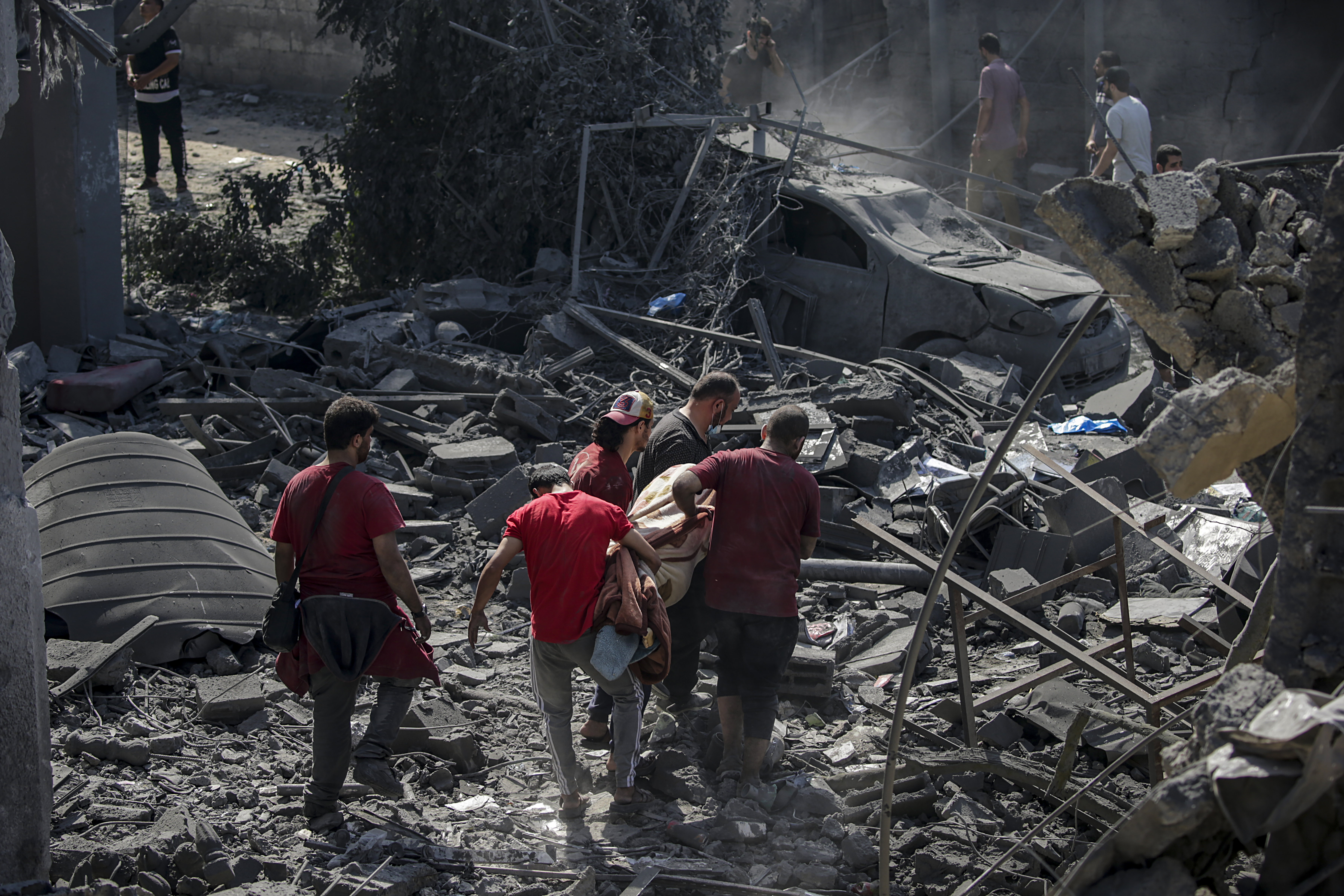 Palestinians recover a body from the rubble of the destroyed Al Shawa family house following an airstrike in Gaza