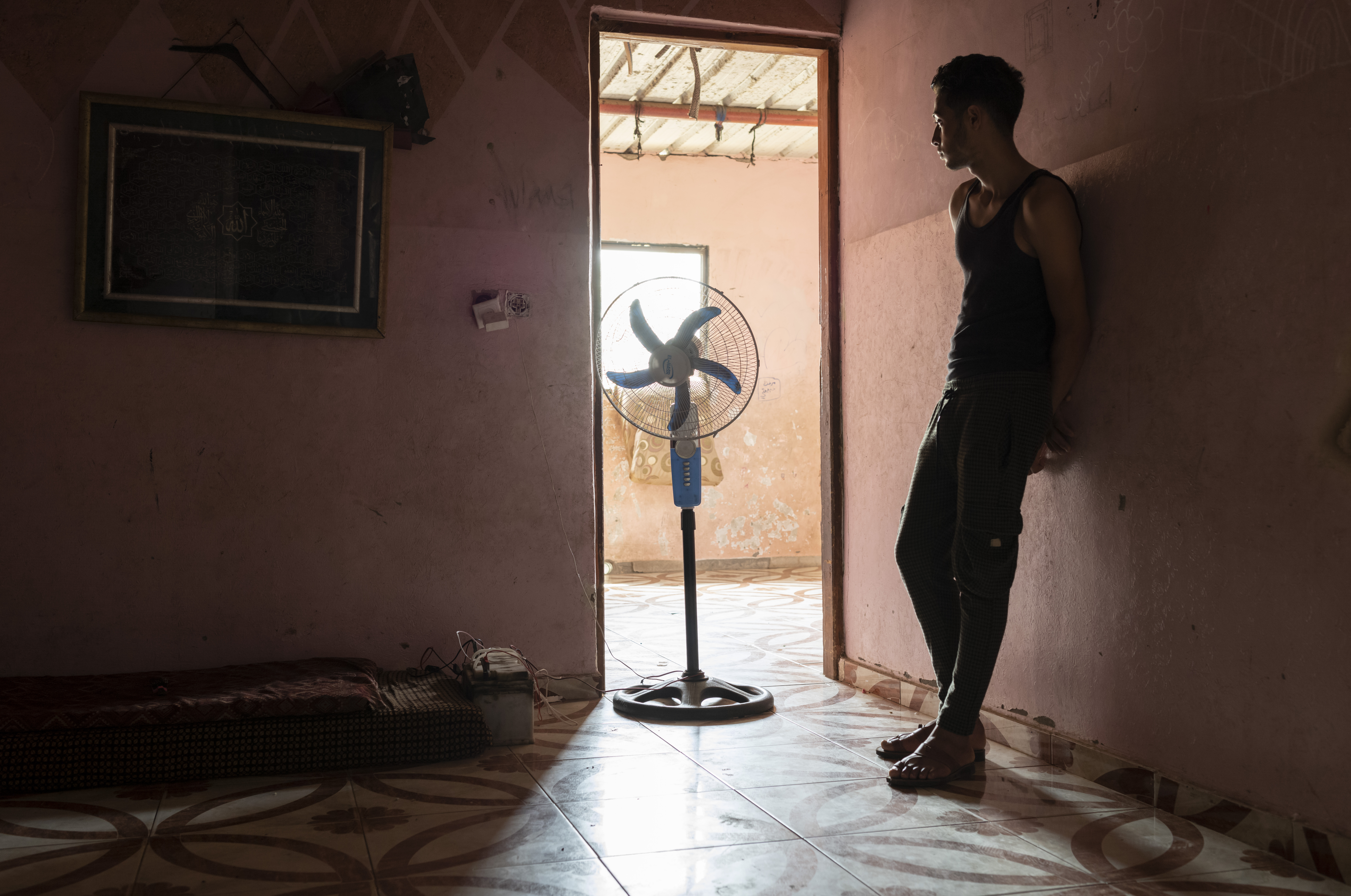 A boy standing near a fan