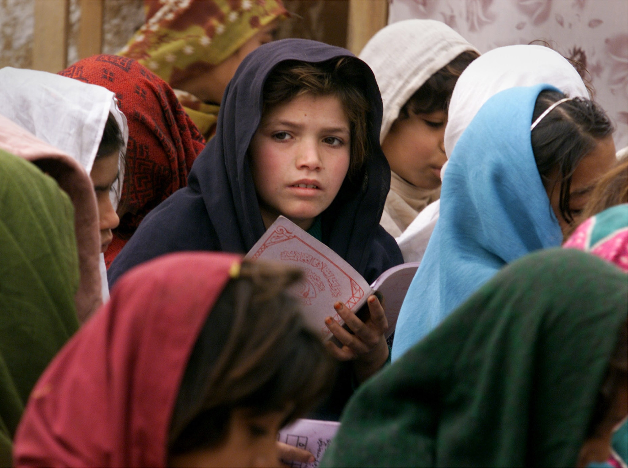 An Afghan refugee girl sits with classmates at an open-air class at a UNESCO-sponsored school on the outskirts of Pakistan capital Islamabad.