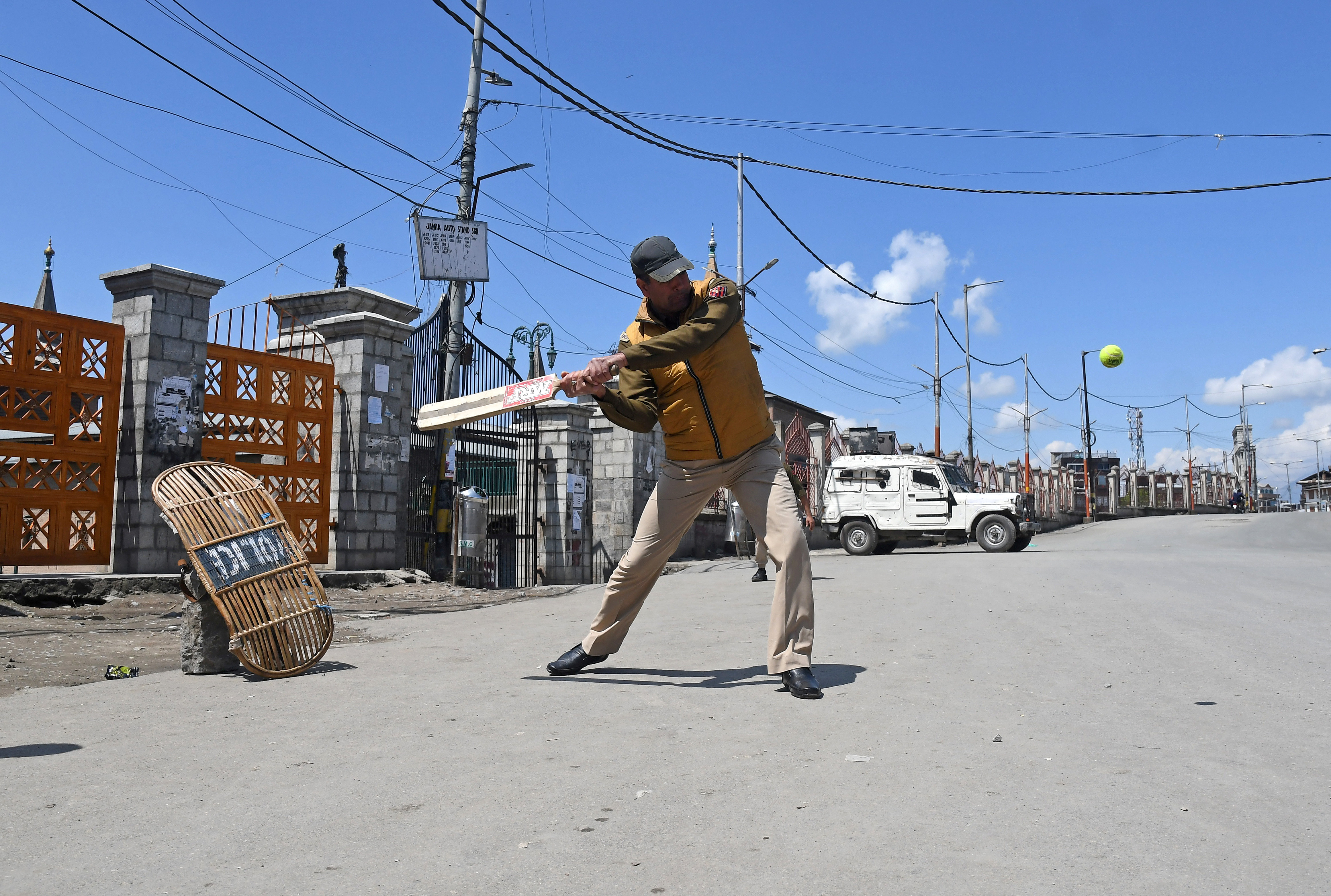 An Indian police officer plays cricket on a deserted road in downtown Srinagar