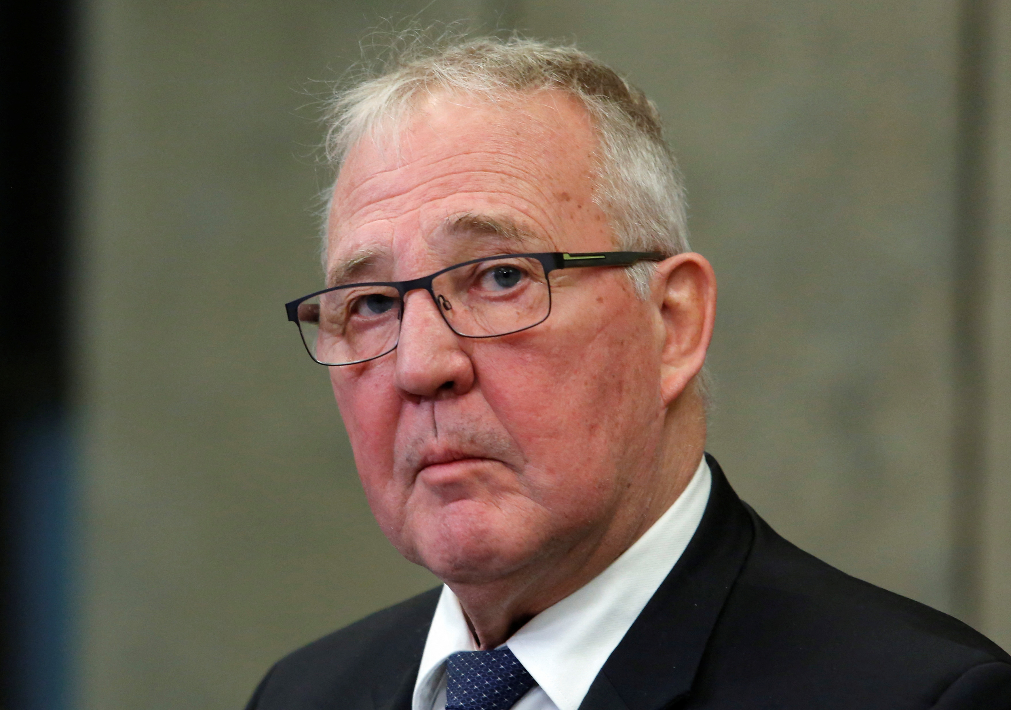 a man in a suit with glasses and frown on face