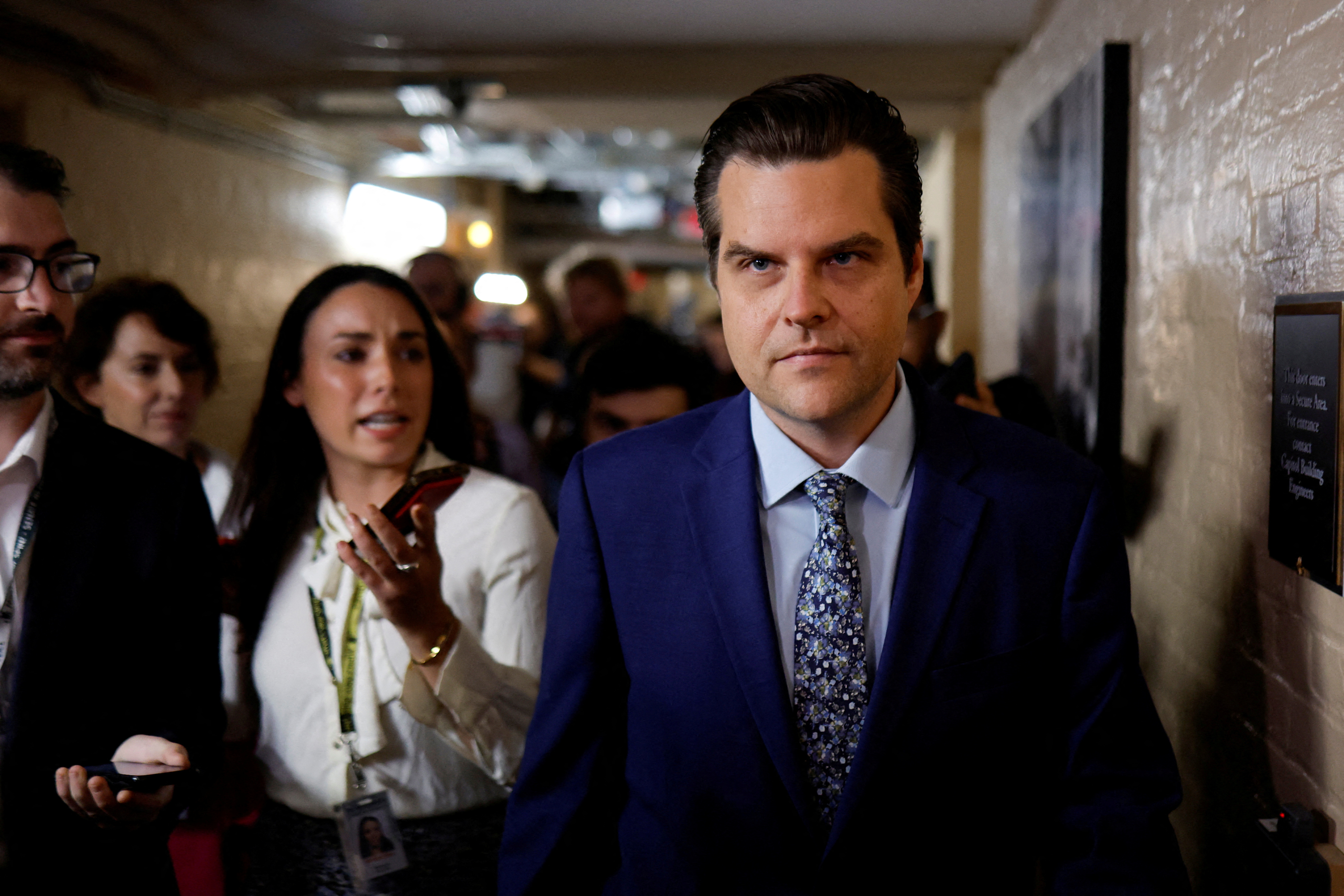 Matt Gaetz striding along a corridor followed by reporters