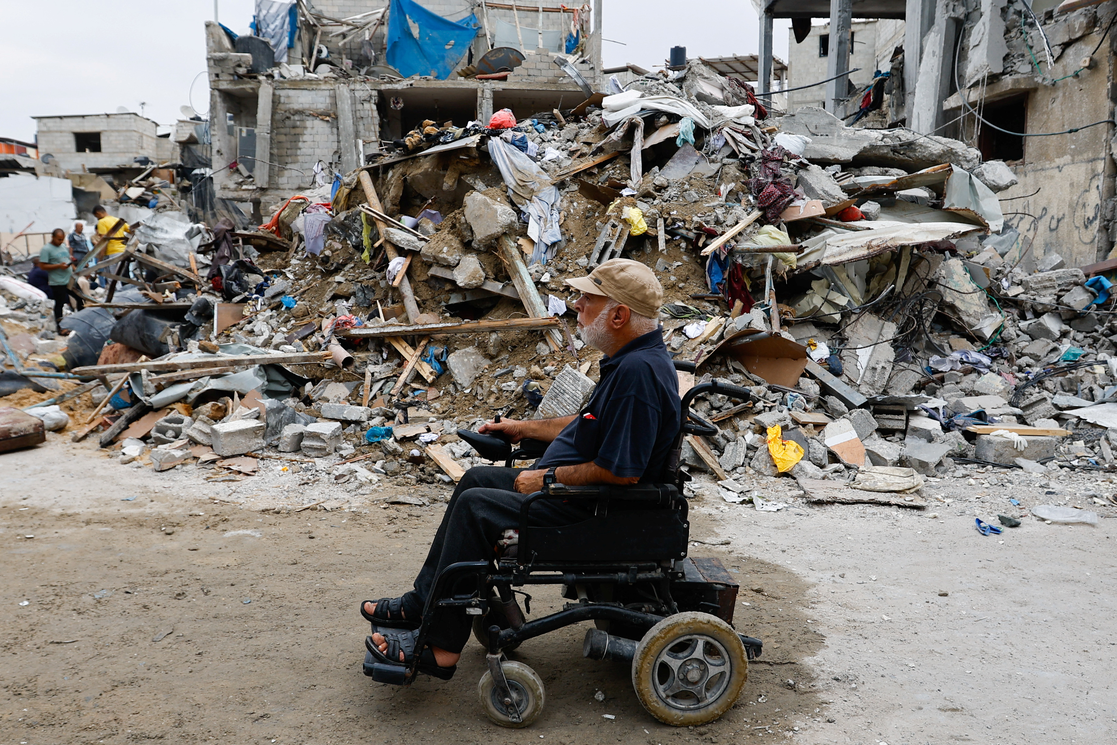 A Palestinian on a wheelchair passes by ruins of buildings destroyed in Israeli attacks, in Rafah in the southern Gaza Strip