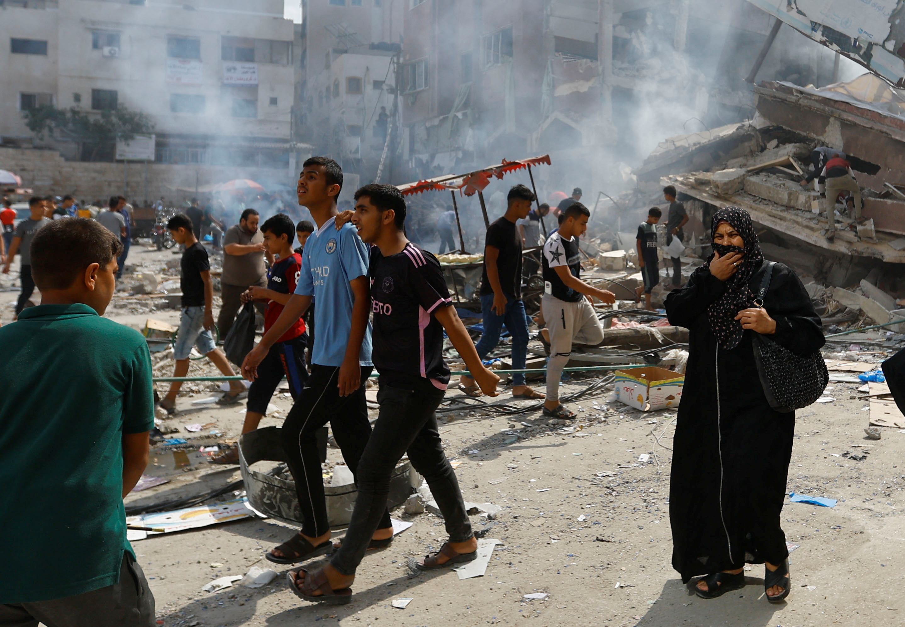 Palestinians walk past destroyed buildings in the aftermath of Israeli strikes in Khan Younis