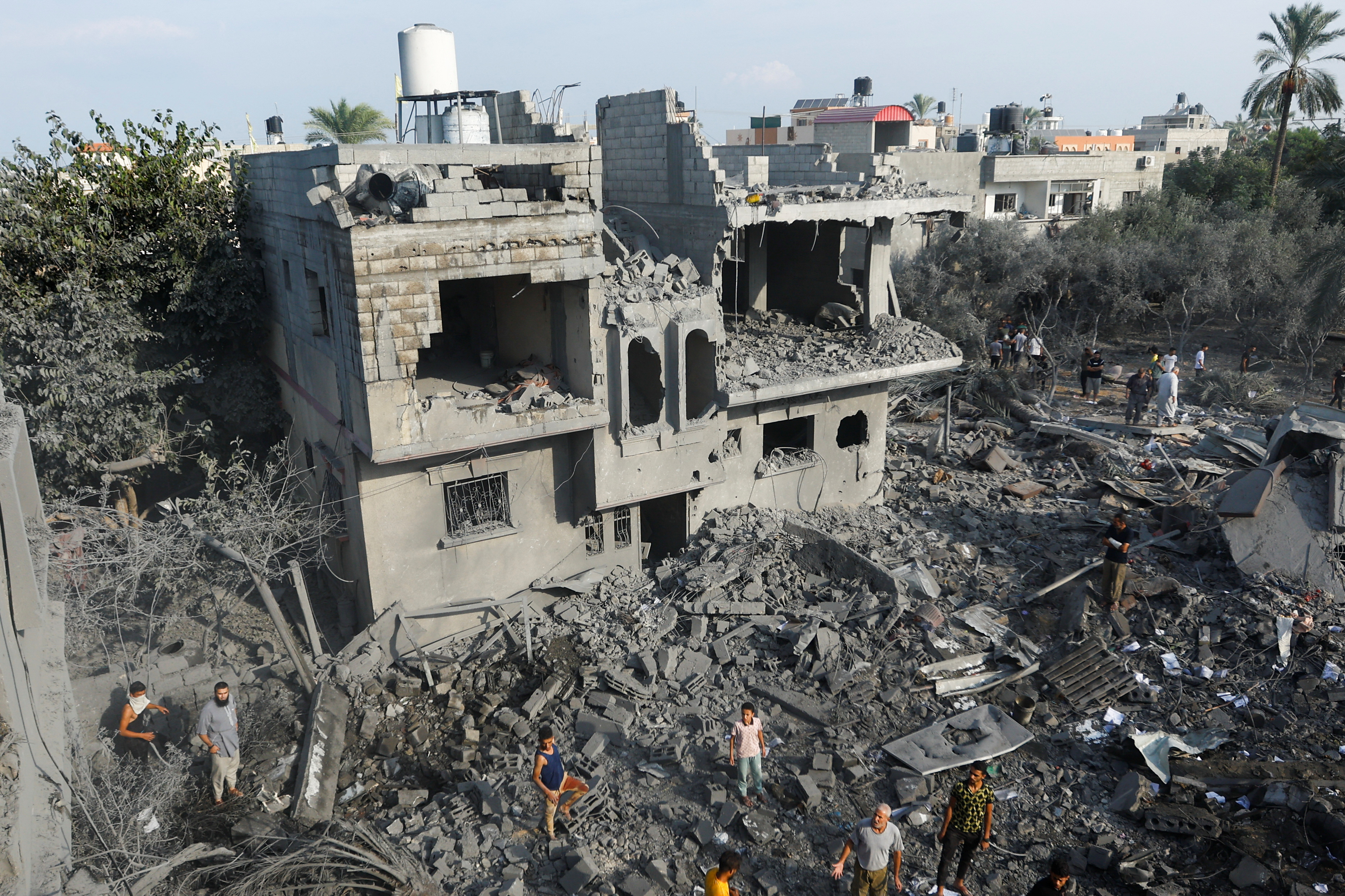 Palestinians gather on rubble near damaged buildings in the aftermath of Israeli strikes, in Khan Younis in the southern Gaza Strip