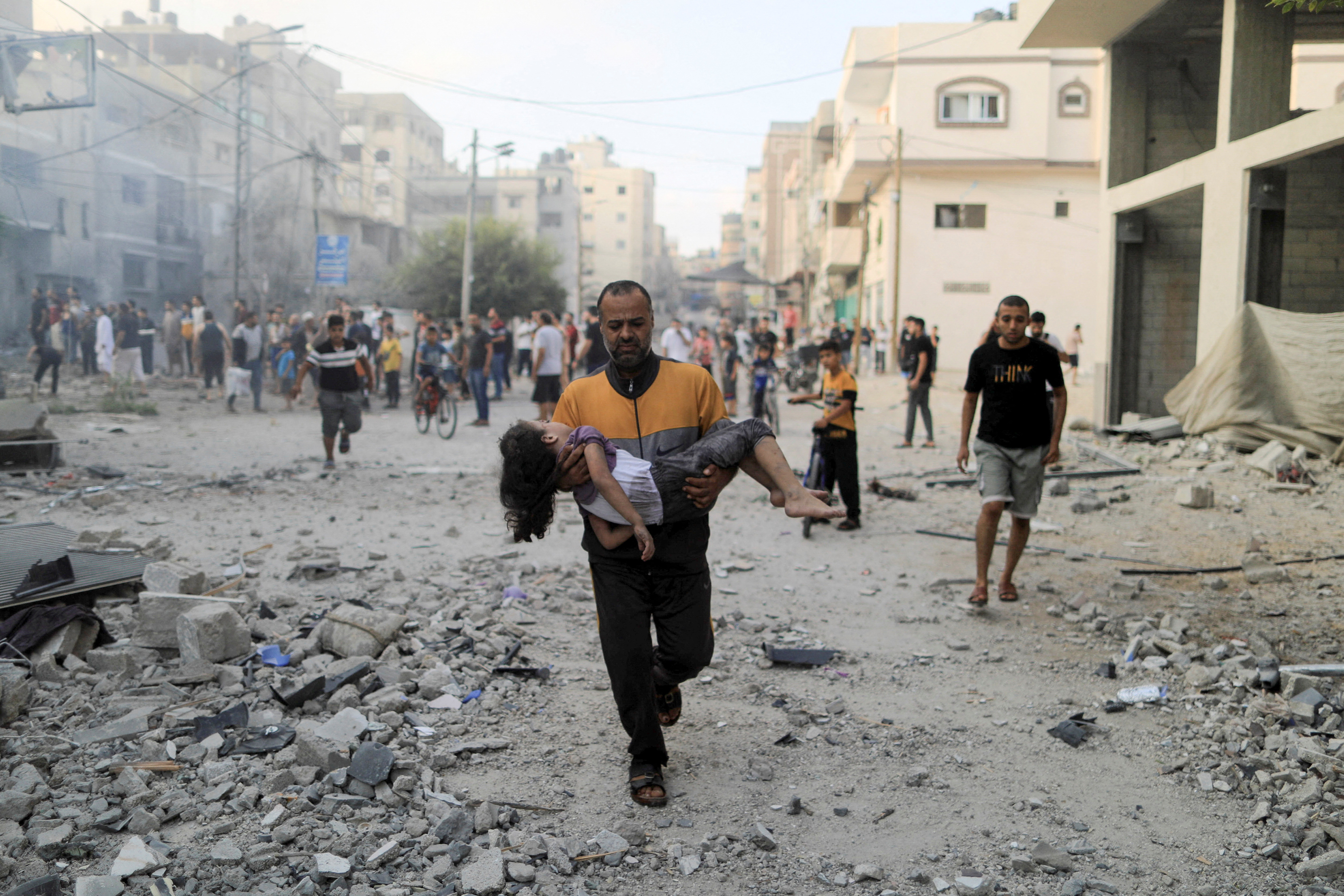 A Palestinian man carries a wounded girl at the site of Israeli strikes, in Khan Younis in the southern Gaza