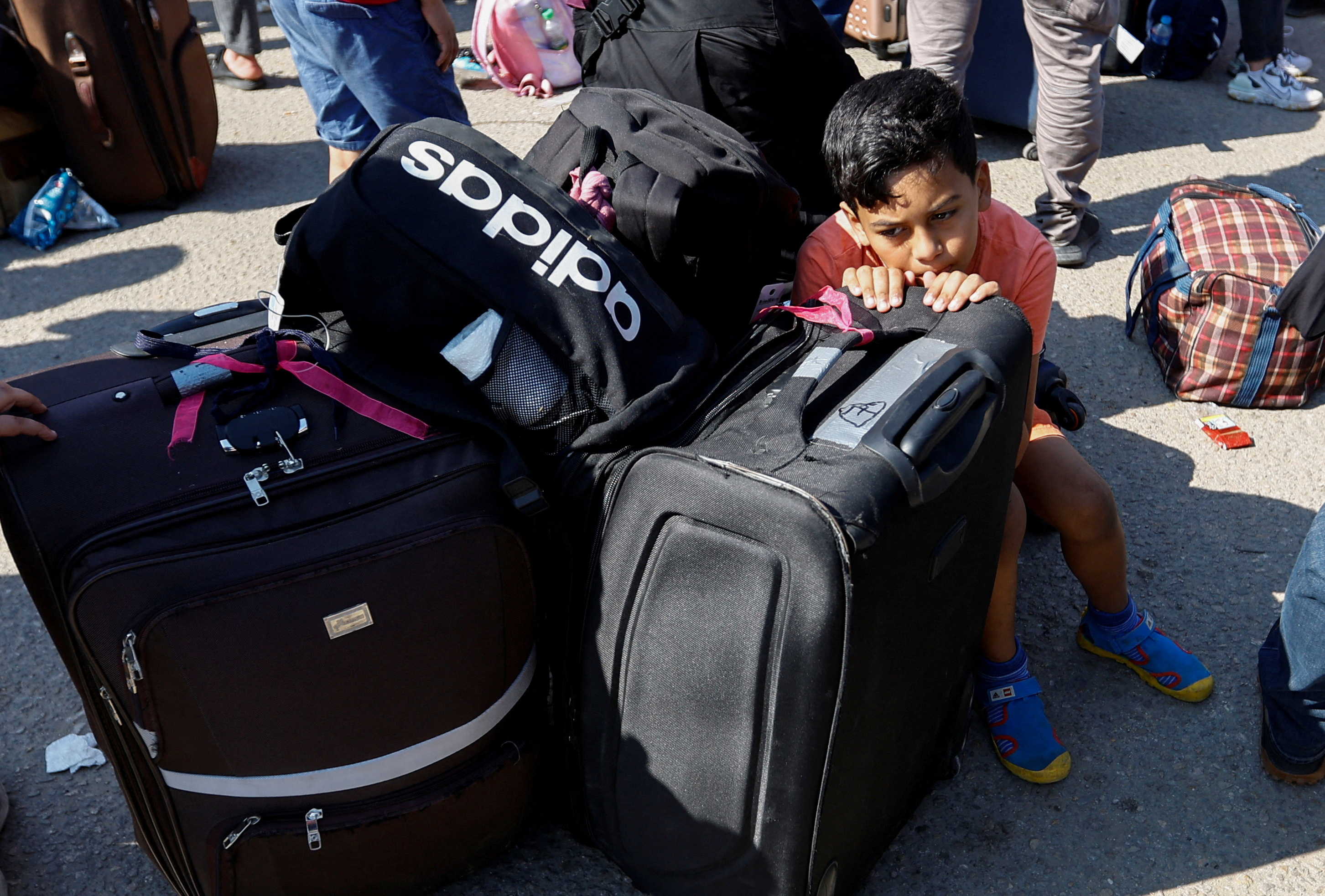 A child rests on luggage as Palestinians with dual citizenship gather outside Rafah border crossing with Egypt in the hope of getting permission to leave Gaza, amid the ongoing Israeli-Palestinian conflict, in Rafah in the southern Gaza Strip