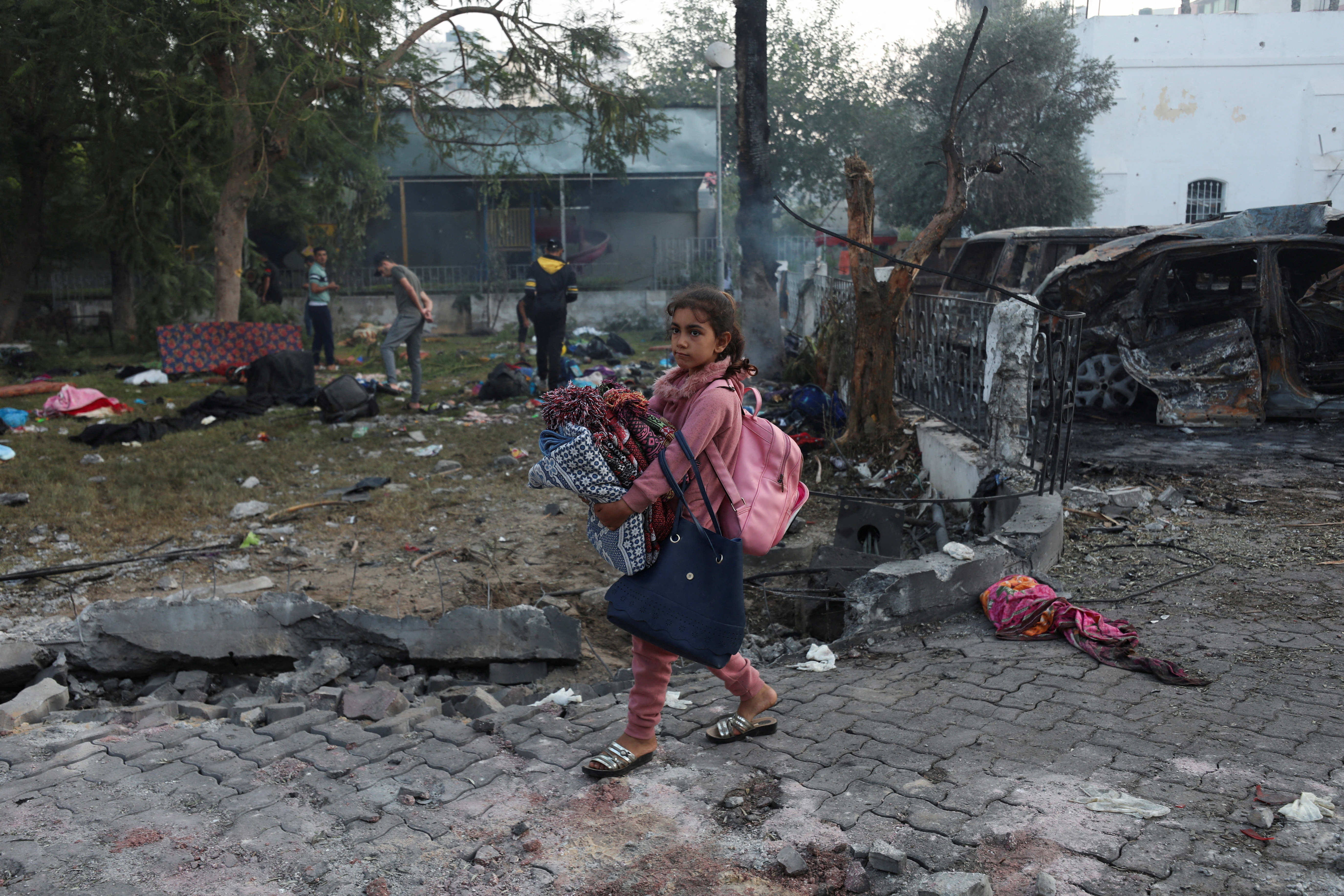 A girl carrying her belongings walks in the area of Al-Ahli hospital where hundreds of Palestinians were killed in a blast that Israeli and Palestinian officials blamed on each other, and where Palestinians who fled their homes were sheltering amid the ongoing conflict with Israel, in Gaza City, October 18, 2023.