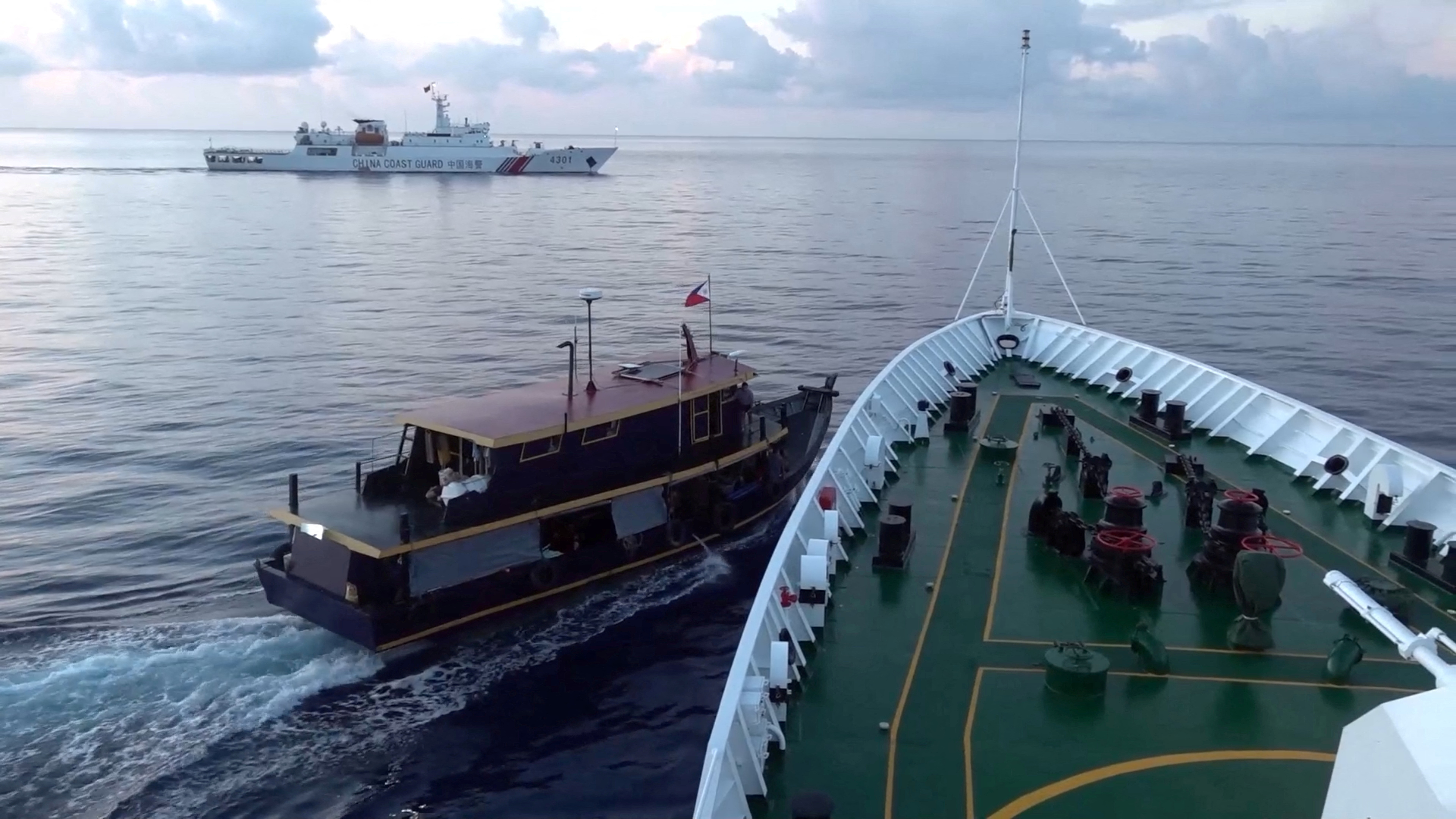 The small wooden boat from the Philippines near the bow of the Chinese coast Coast Guard ship