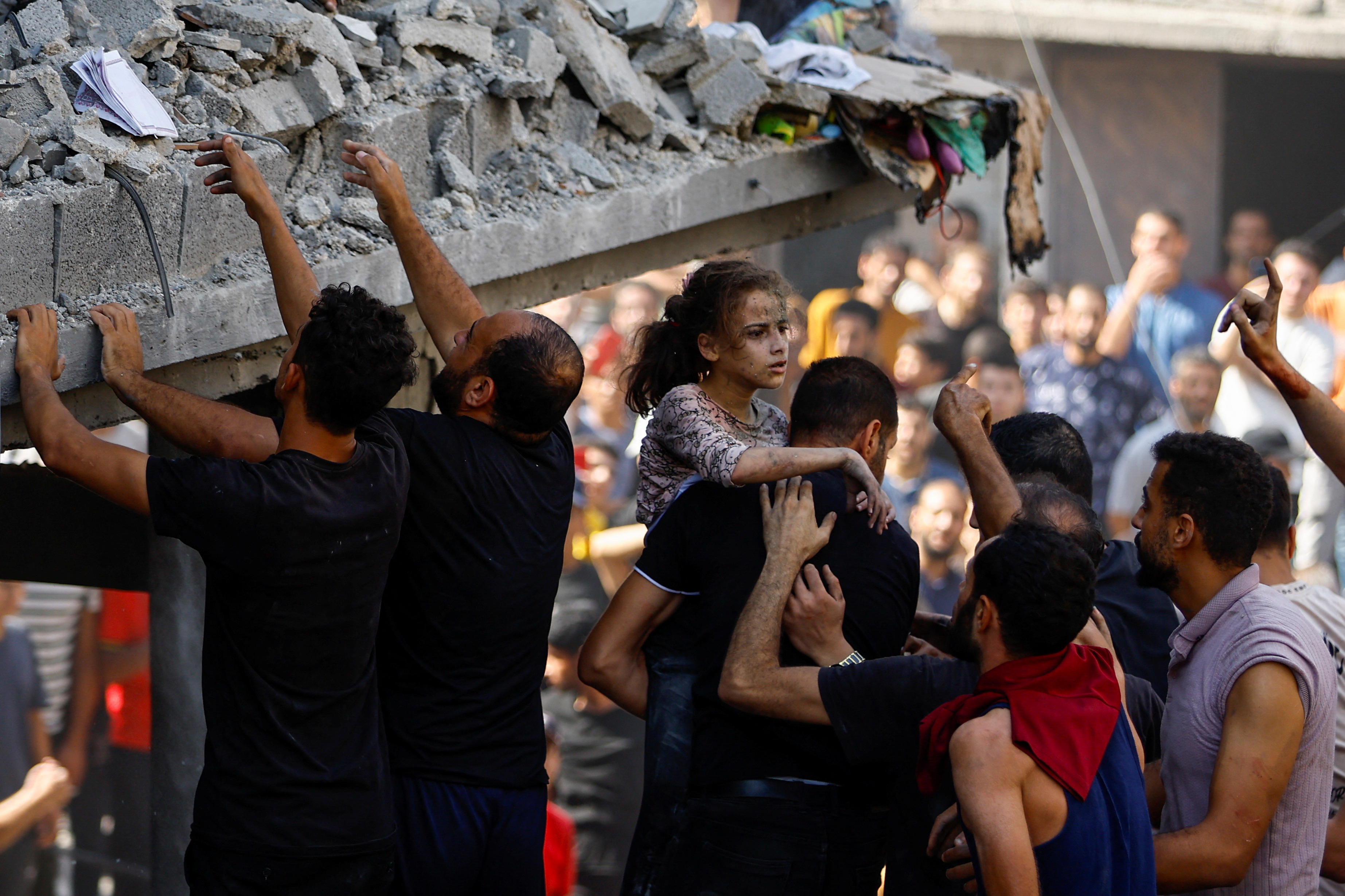 A Palestinian carries a child casualty at the site of an Israeli strike