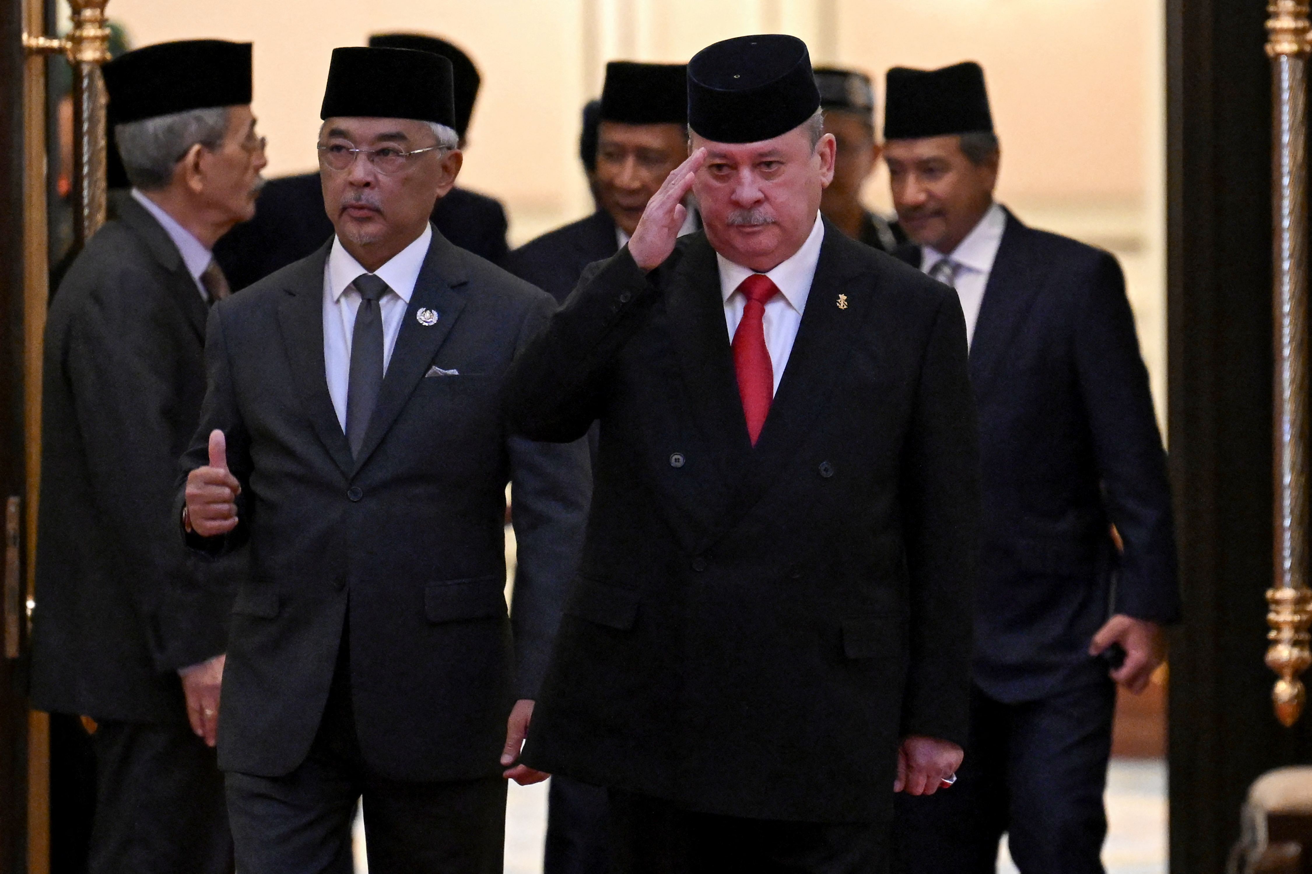 Malaysia's King Sultan Abdullah Sultan Ahmad Shah and Sultan Ibrahim Iskandar of Johor walking side by side. Sultan Ibrahim is saluting.