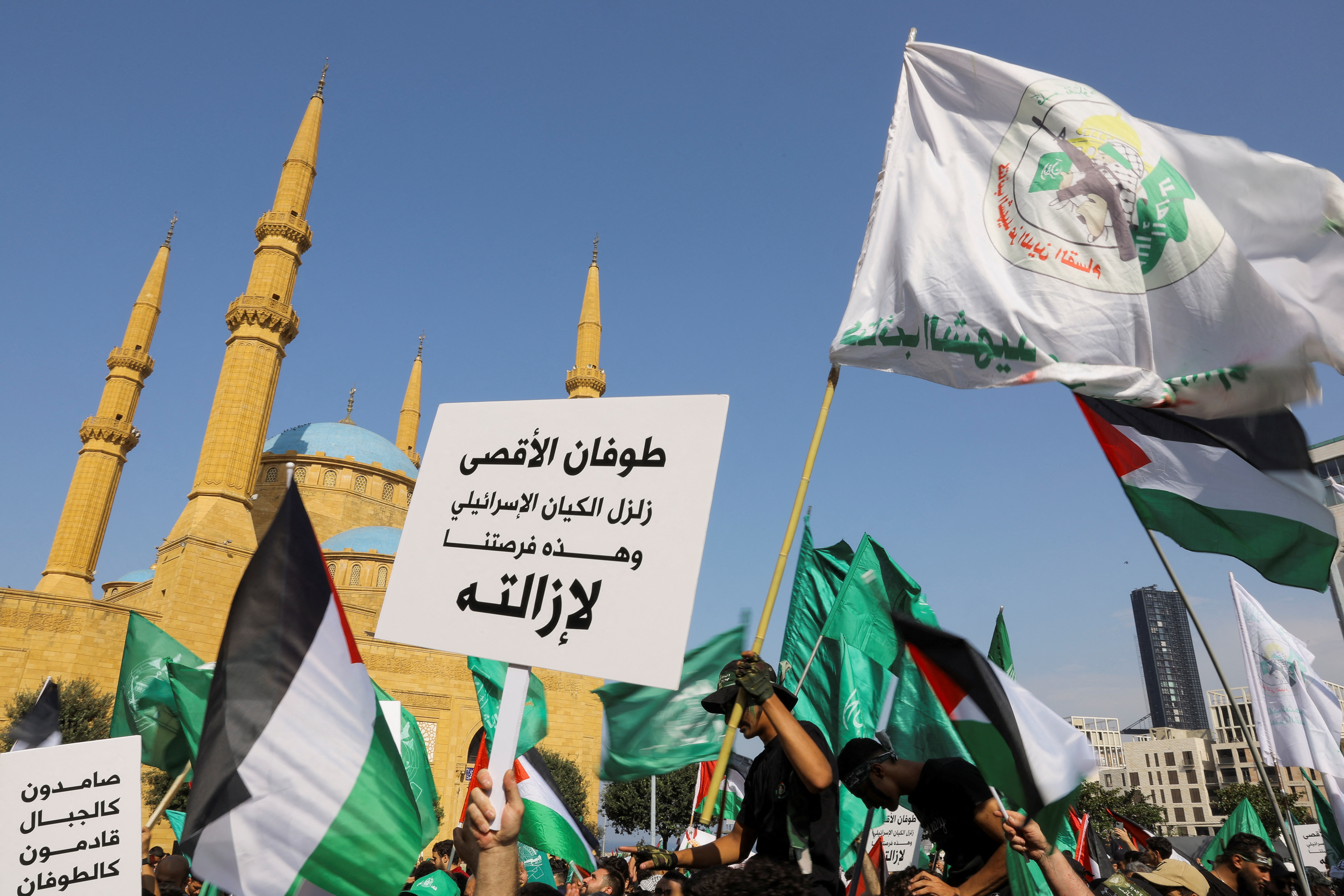 Protesters waving Palestinian flags protest with picket signs in front of the Al-Amin mosque.