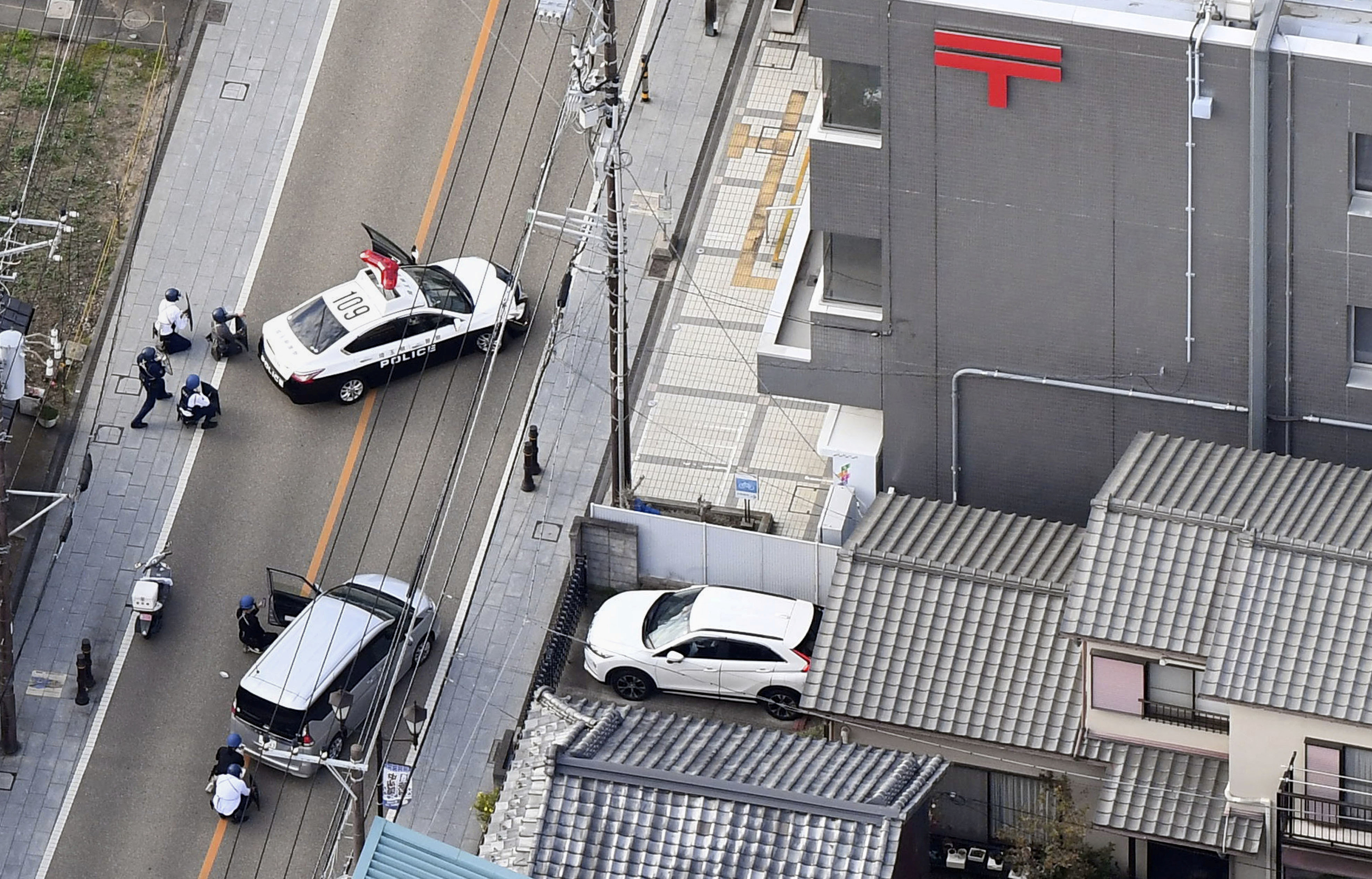 Police officers take cover behind cars outside the post office where a suspected gunman has taken people hostage after injuring two at a hospital, in Warabi, Saitama Prefecture, Japan October 31, 2023, in this photo taken by Kyodo. Mandatory credit Kyodo/via REUTERS ATTENTION EDITORS - THIS IMAGE HAS BEEN SUPPLIED BY A THIRD PARTY. MANDATORY CREDIT. JAPAN OUT. NO COMMERCIAL OR EDITORIAL SALES IN JAPAN.