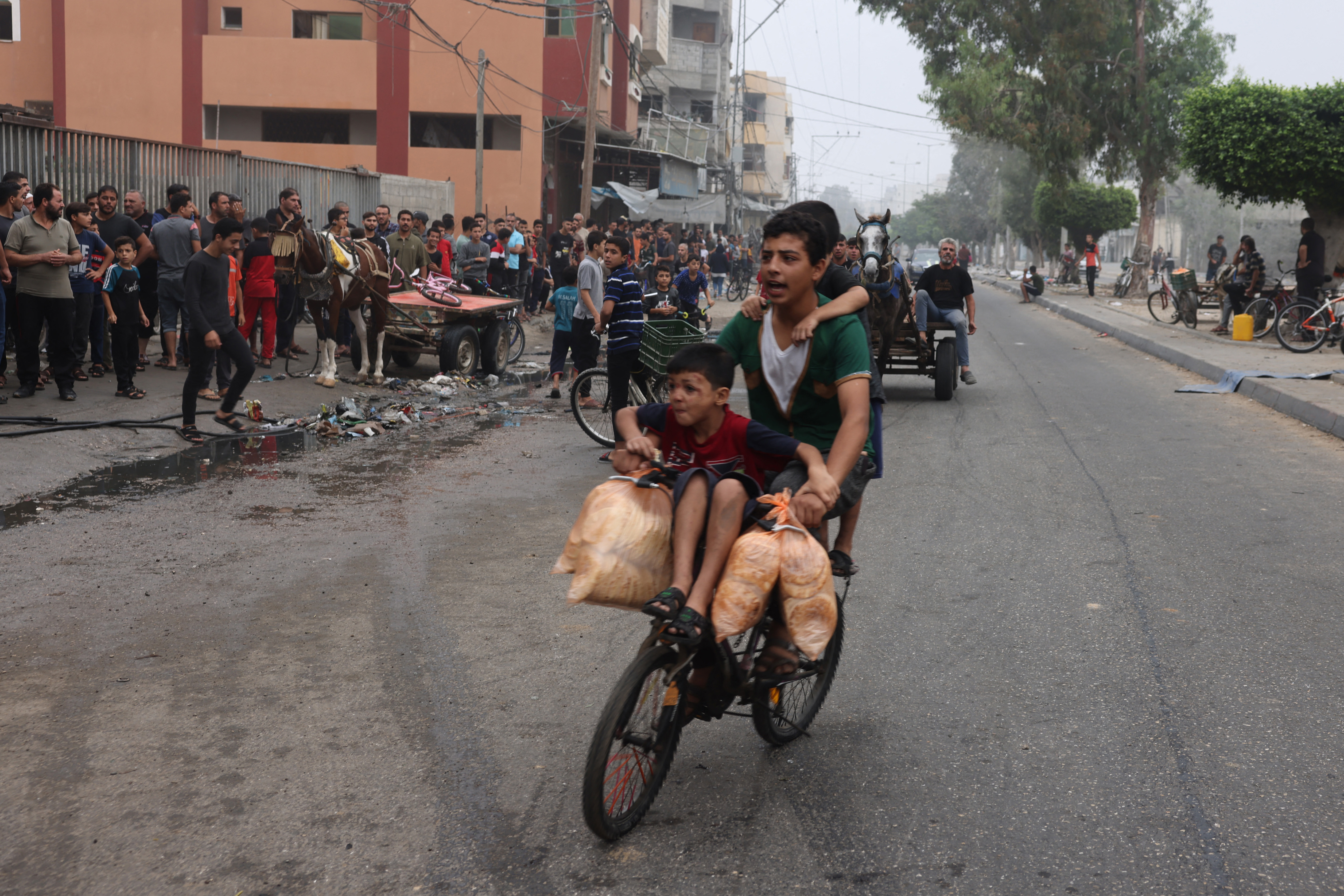 Youngsters carry bags of bread as they ride a bicycle in Rafah in the southern Gaza Strip