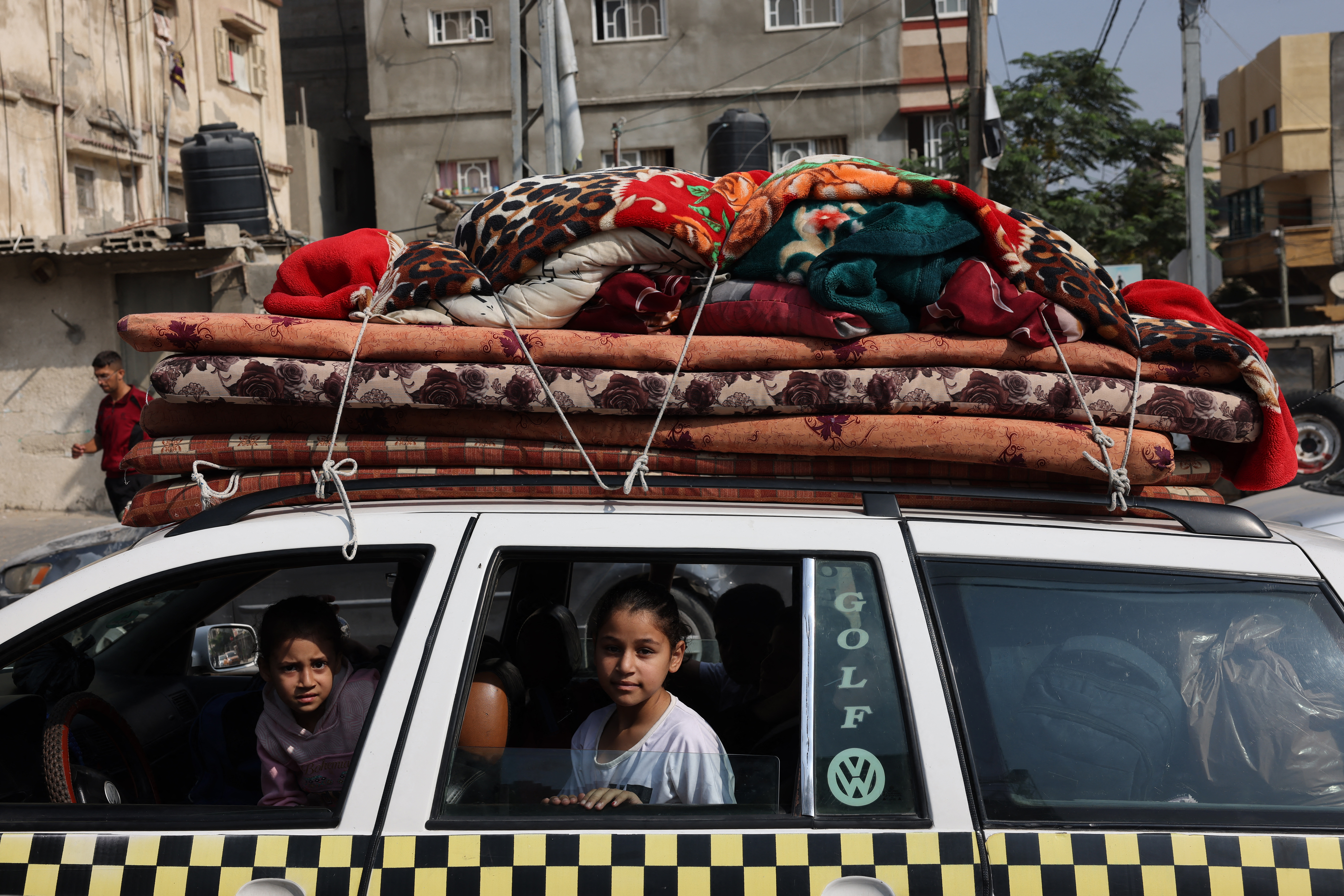 Palestinian children sit in a vehicle loaded with house hold items in Khan Yunis refugee camp, in Khan Yunis