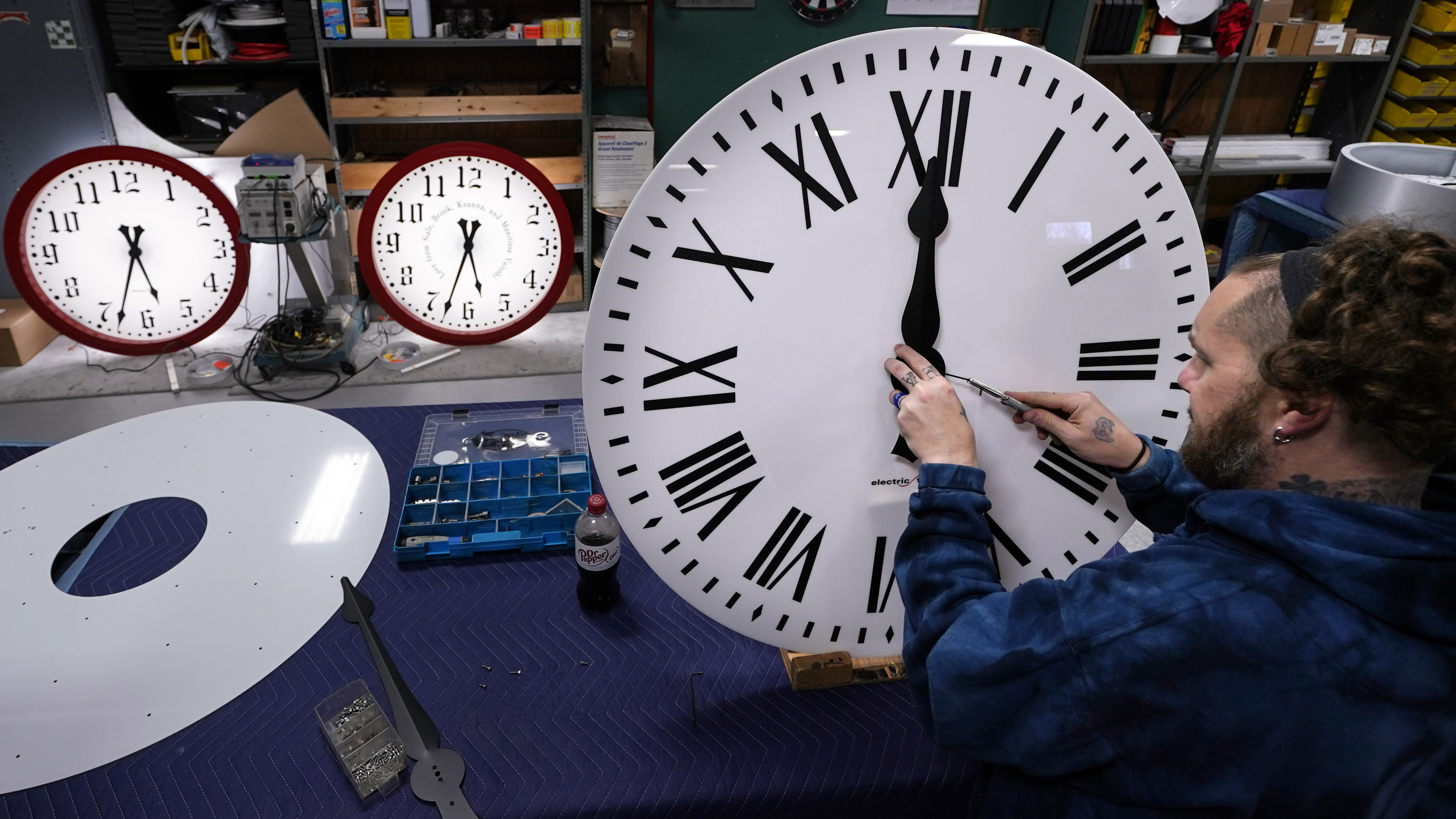 Man fastens the hands to a clock at Electric Time Company, Tuesday, Nov. 1, 2022, in Medfield, Mass. Daylight saving time ends at 2 a.m. local time Sunday, Nov. 6, 2022, when clocks are set back one hour.