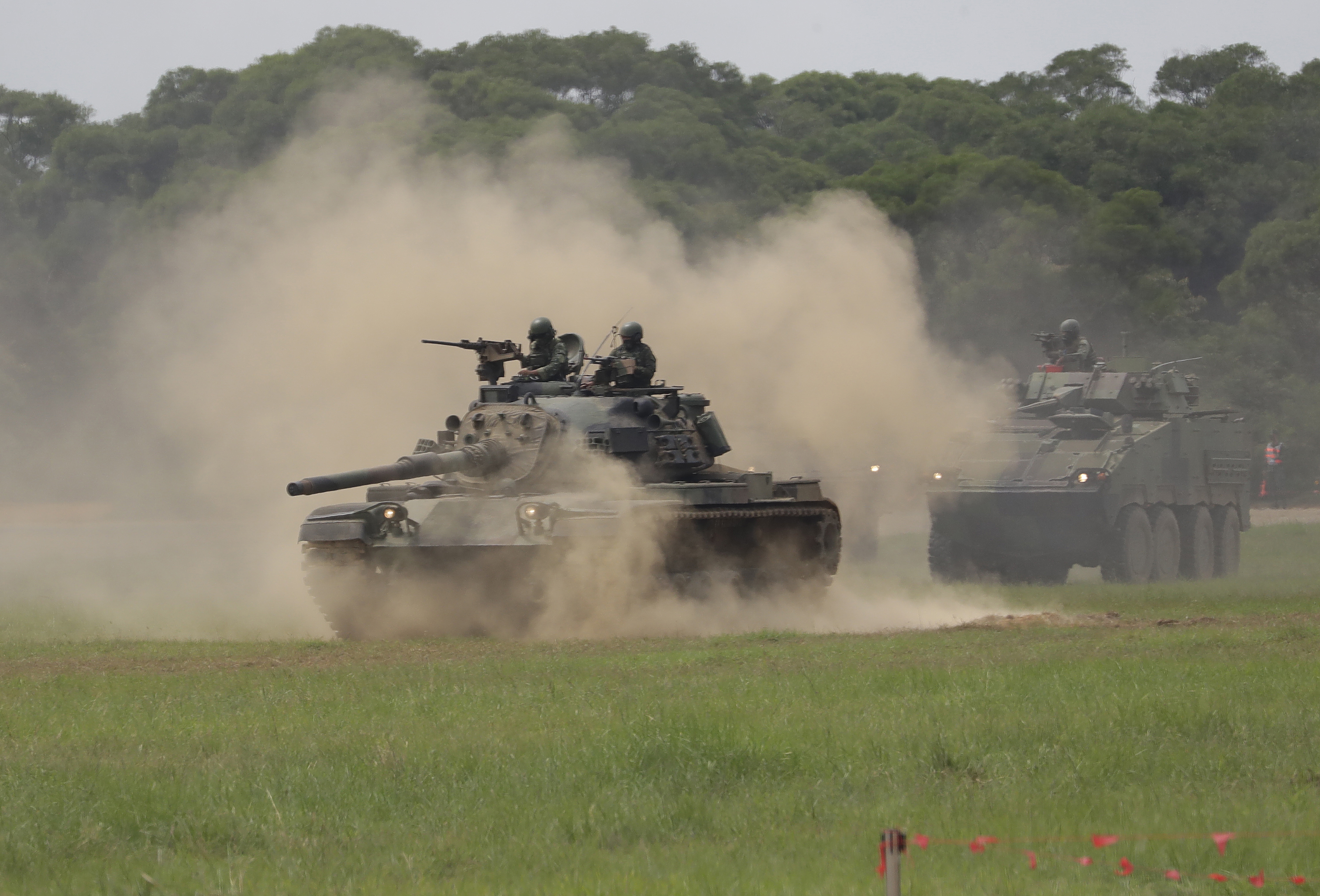 A tank moving through a cloud of dust