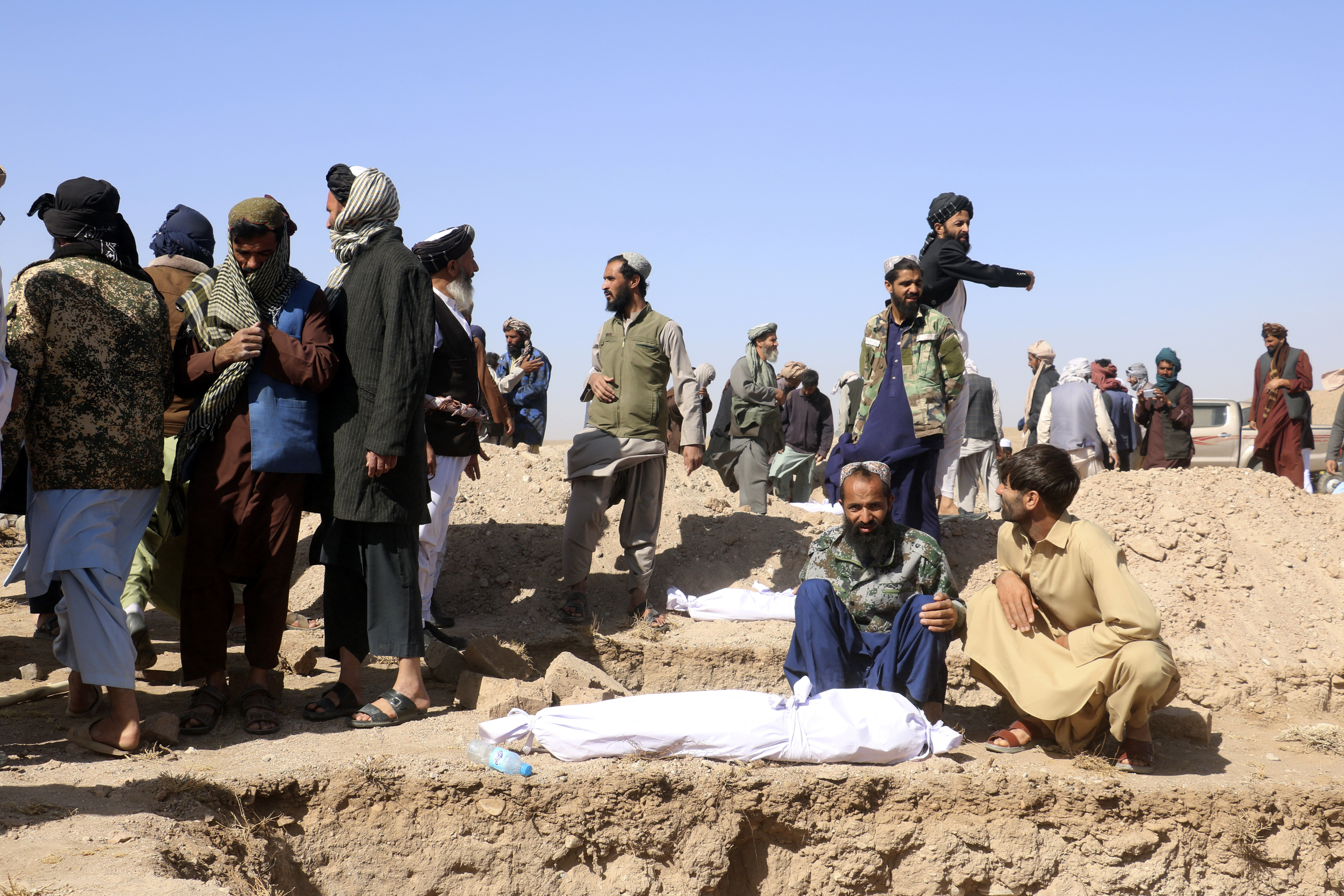 Afghan men bury the victims after an earthquake in Zenda Jan district in Herat province, of western Afghanistan