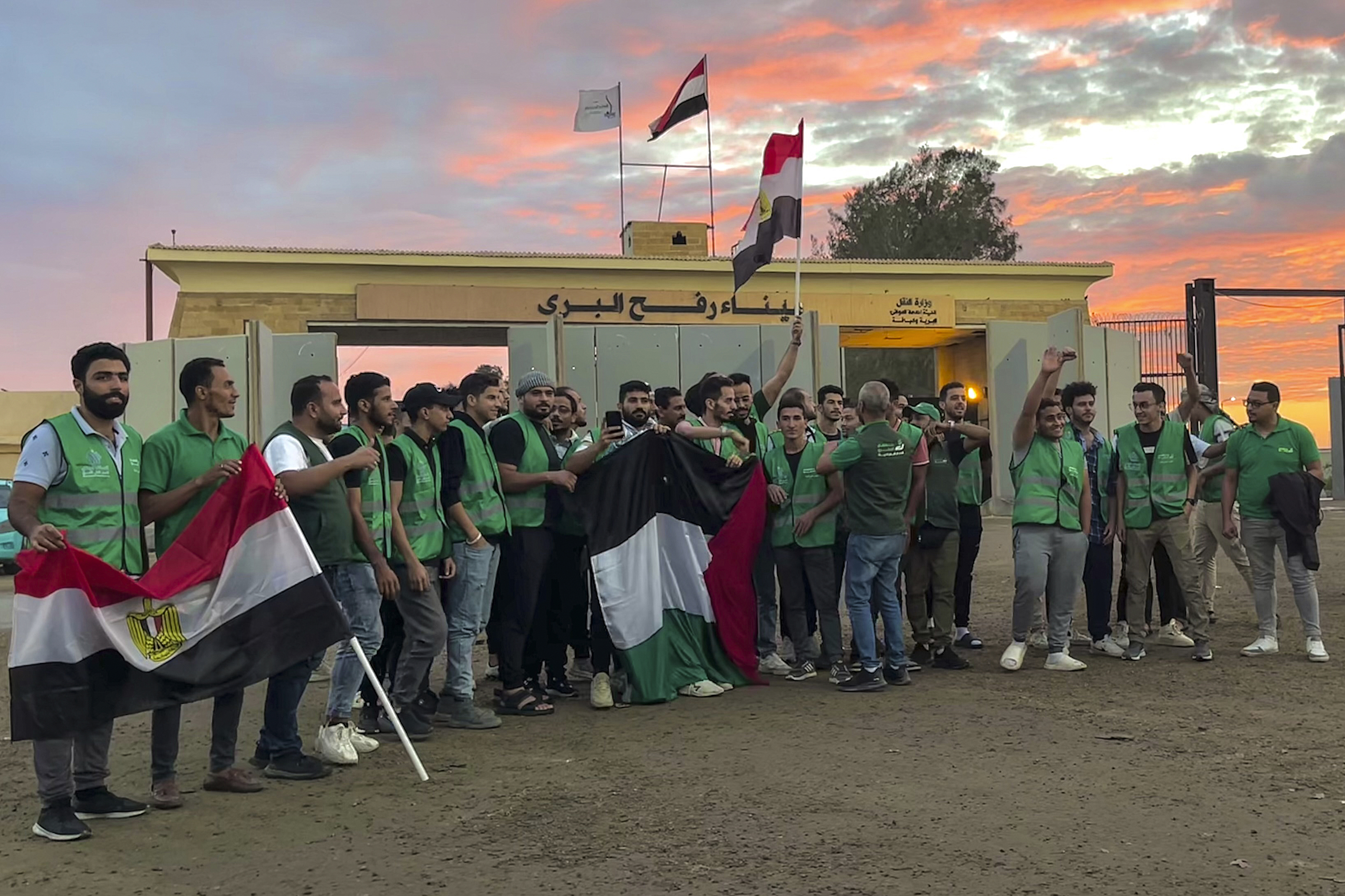 Volunteers of the humanitarian aid convoy for the Gaza Strip wave Egyptian and Palestinian flags at Rafah crossing port, Egypt, Tuesday, Oct. 17, 2023. Hundreds of Palestinians in the Gaza Strip have fled their homes ahead of an expected Israeli ground invasion aimed at destroying Hamas after its fighters rampaged through southern Israel.