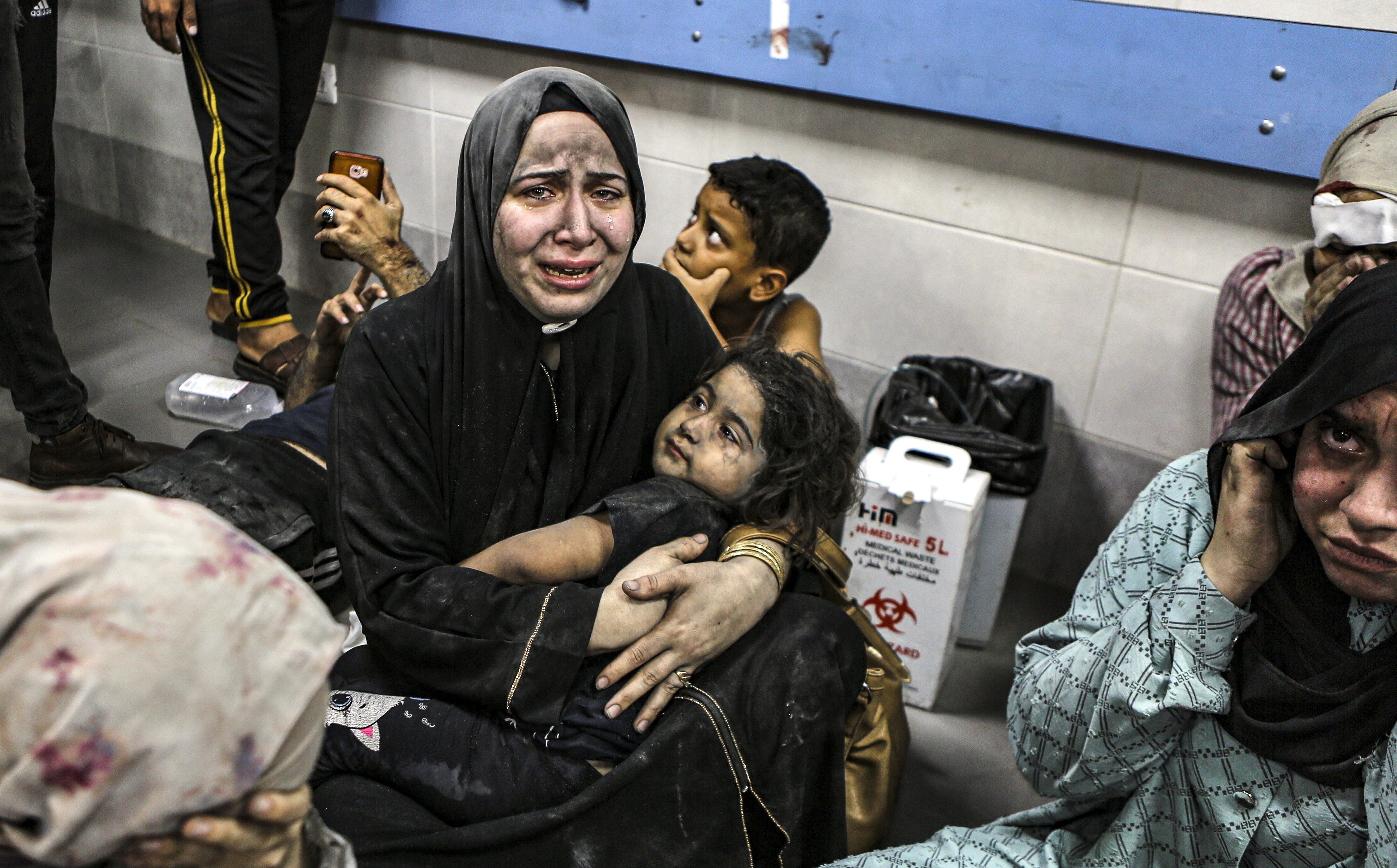 Palestinians wounded at al-Ahli hospital in Gaza sit on the floor at al-Shifa hospital following a deadly air strike blamed on Israel [Abed Khaled/AP]