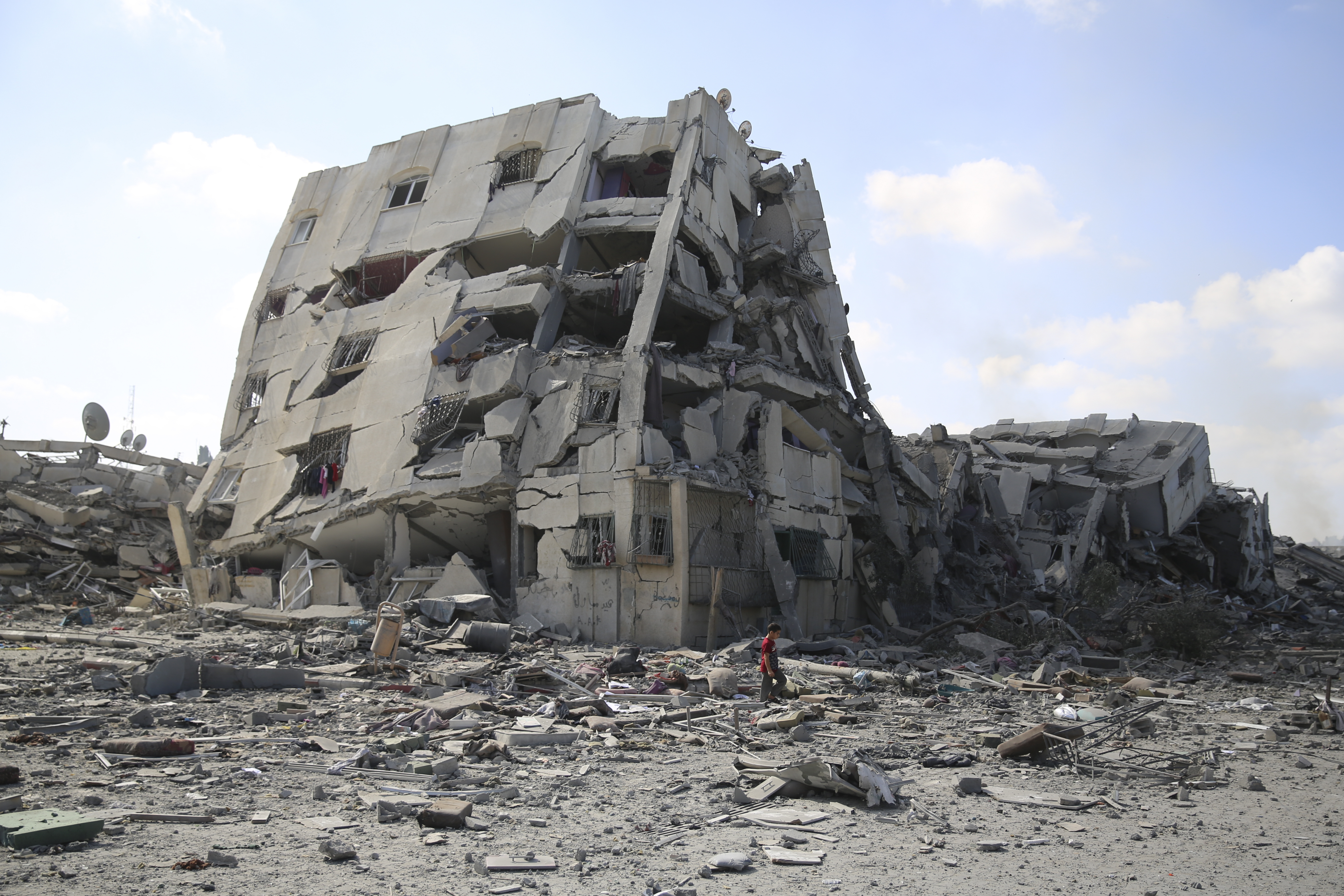 Palestinians boy walks by the buildings destroyed in the Israeli bombardment on al-Zahra, on the outskirts of Gaza City