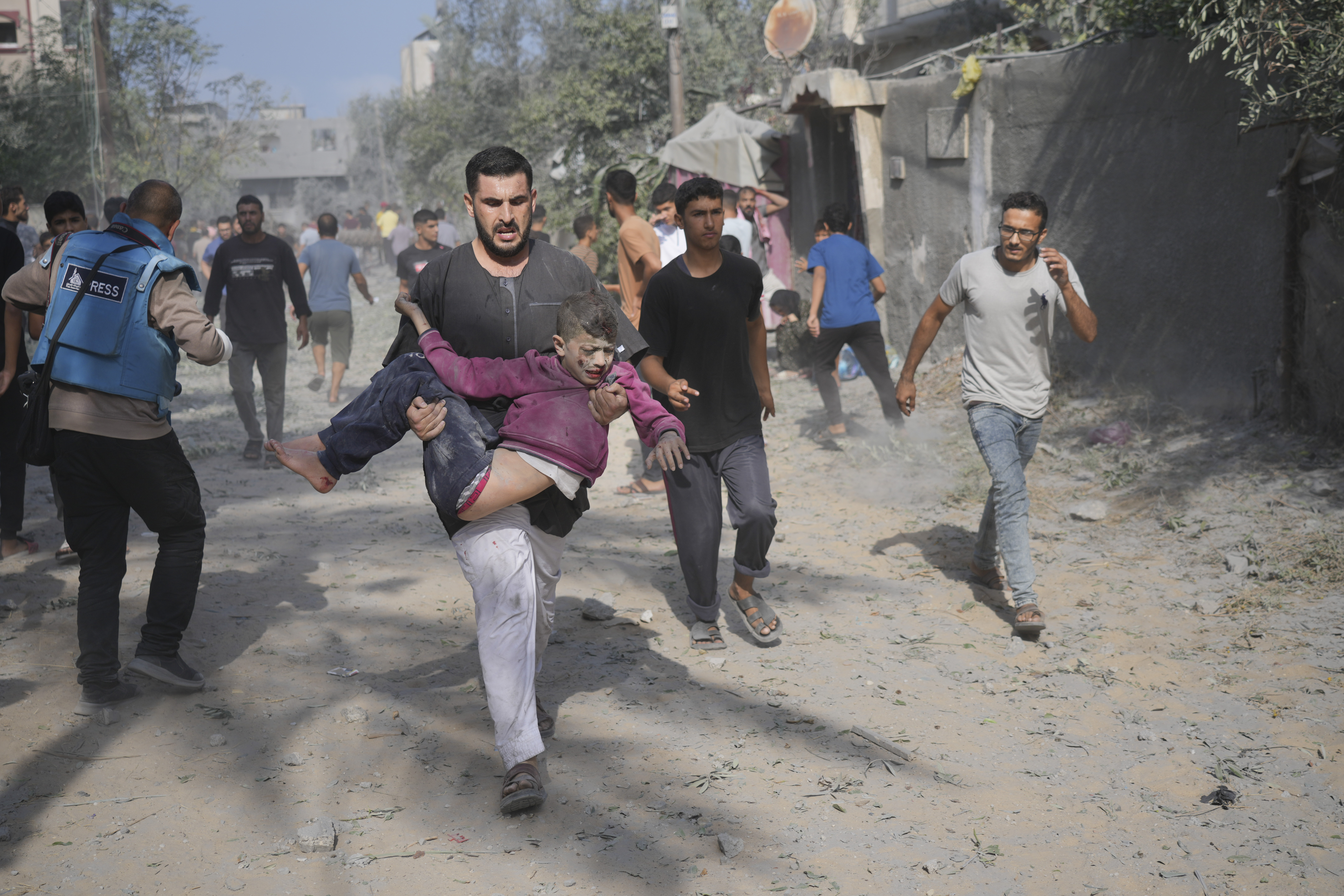 A Palestinian carries a boy wounded during the Israeli bombardment of the Gaza Strip in Deir Al-Balah