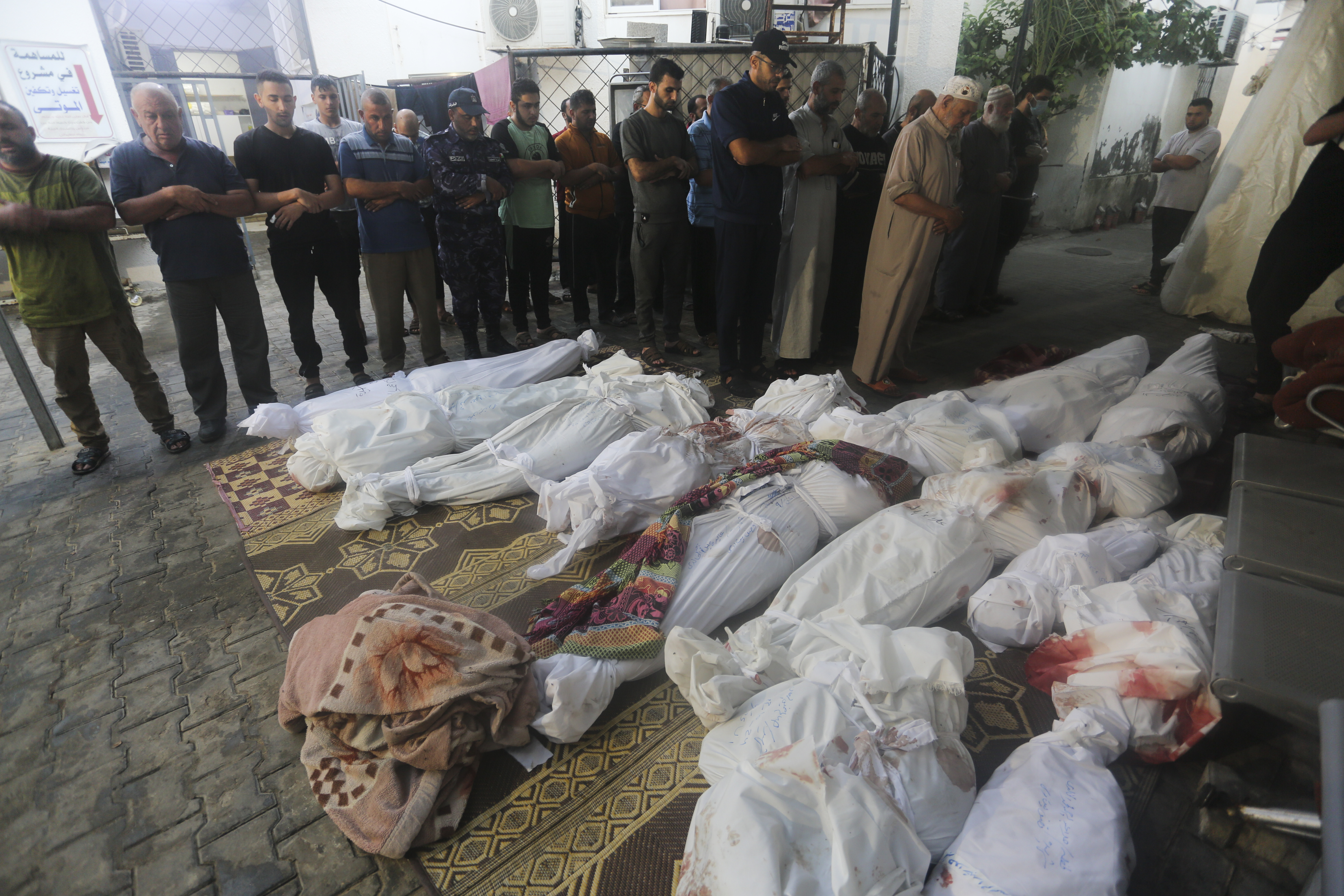 Palestinians pray by the bodies of people killed in the Israeli bombardment of the Gaza Strip in Rafah