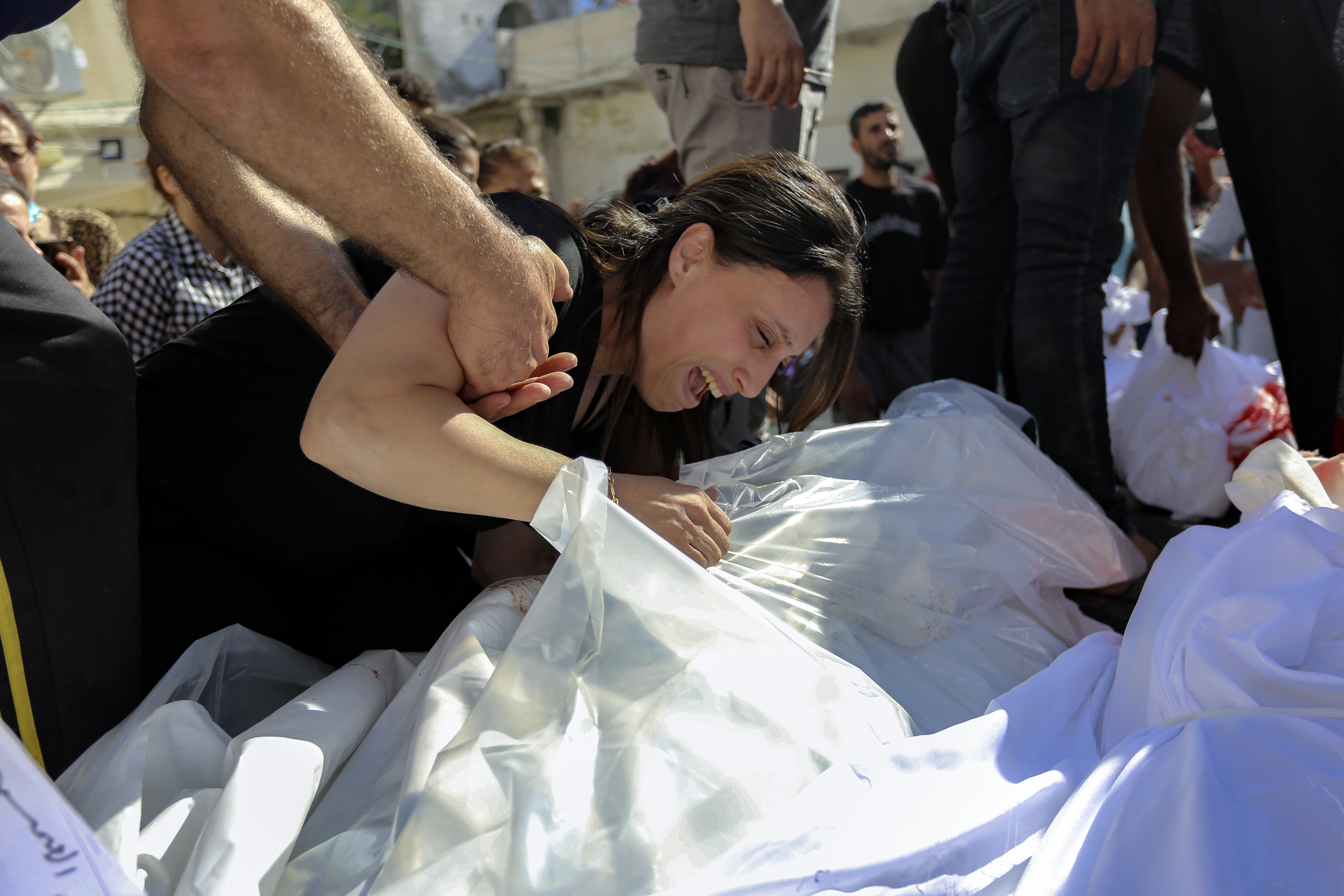 A Palestinian woman mourns over the bodies of her relatives who were killed in Israeli airstrikes that hit a Greek Orthodox church, in Gaza City, Friday