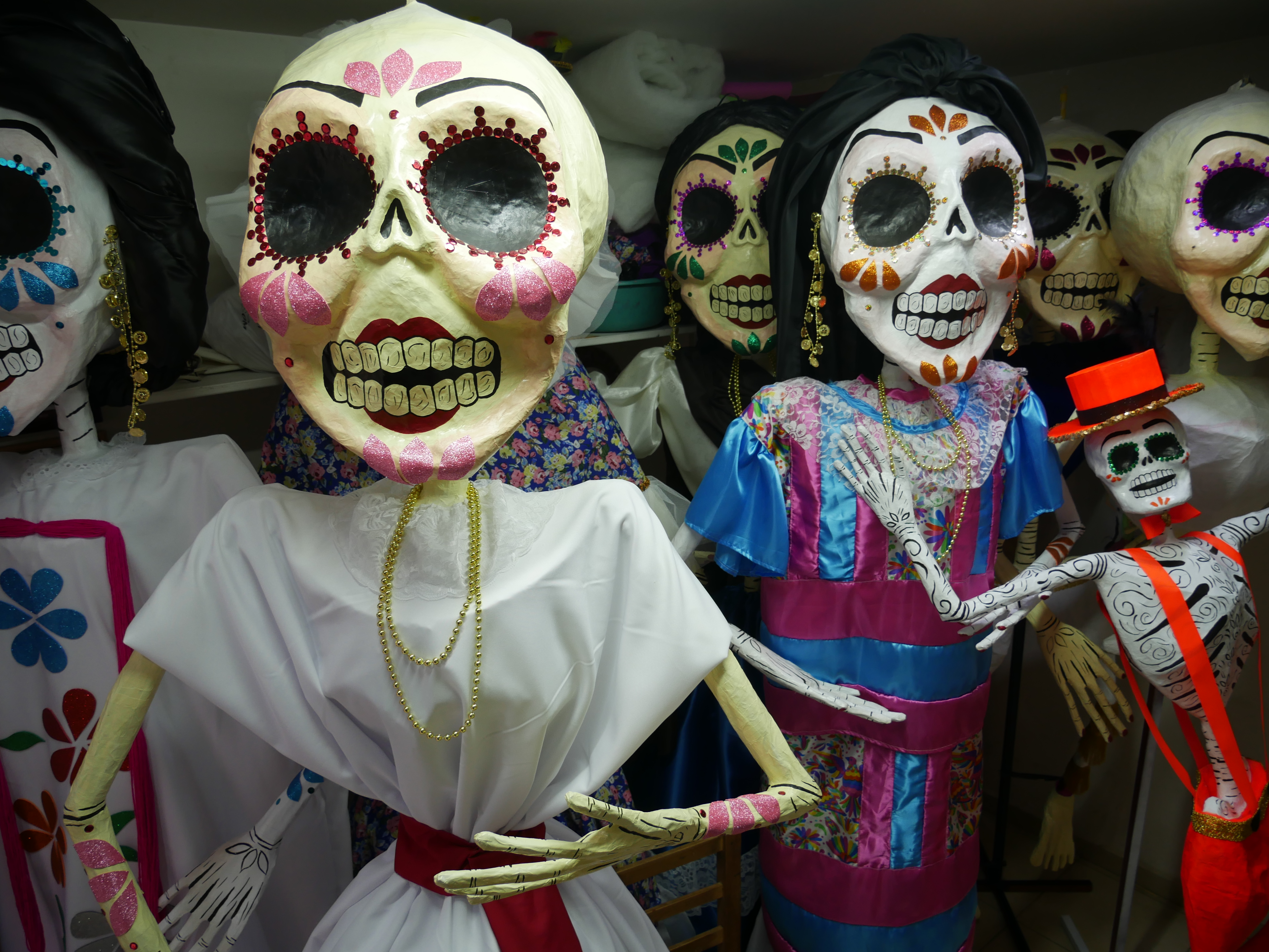 Dolls representing La Calavera Catrina — a brightly decorated skull — stand packed together.