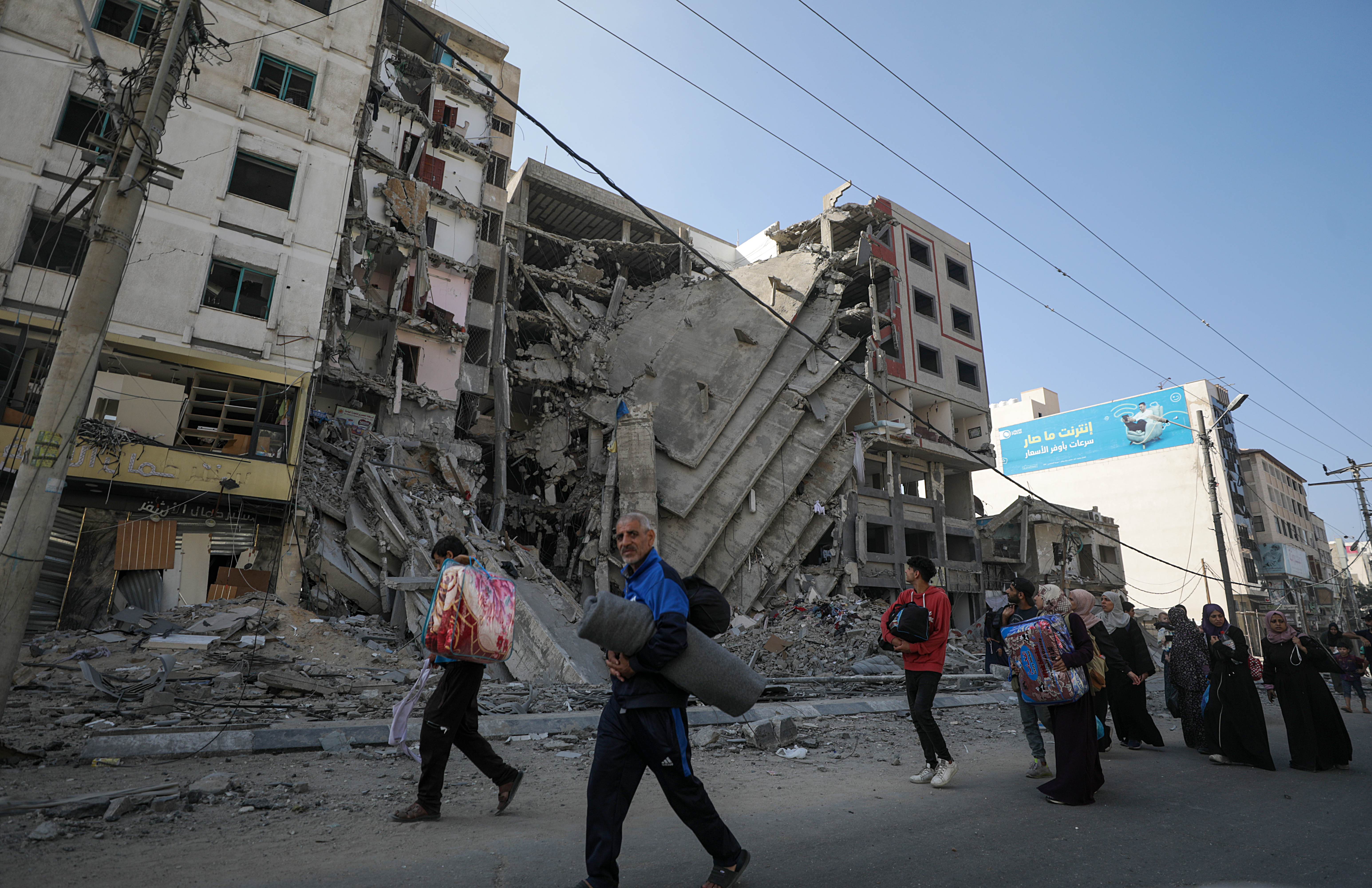 Residents walk past a damaged building as they evacuate Gaza City amid increased military operations in the Gaza Strip.