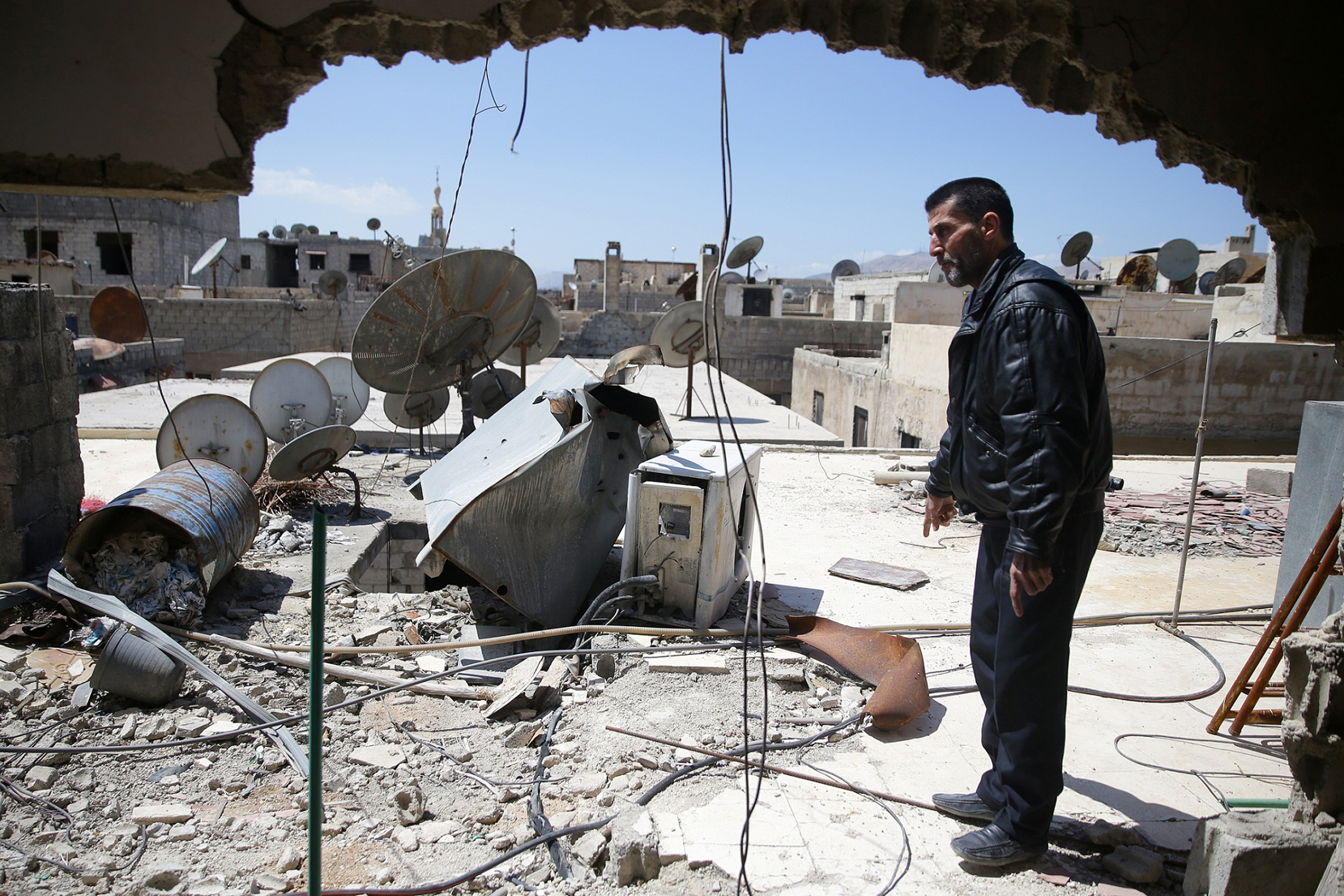 Abu Ghassan, 50, one of the survivors of a chemical attack in the Ghouta region of Damascus that took place in 2013, points at a piece of one of the rockets fired in 2013, as he stands in the Ghouta town of Ain Tarma, Syria April 7, 2017. Picture taken April 7, 2017. REUTERS/Bassam Khabieh
