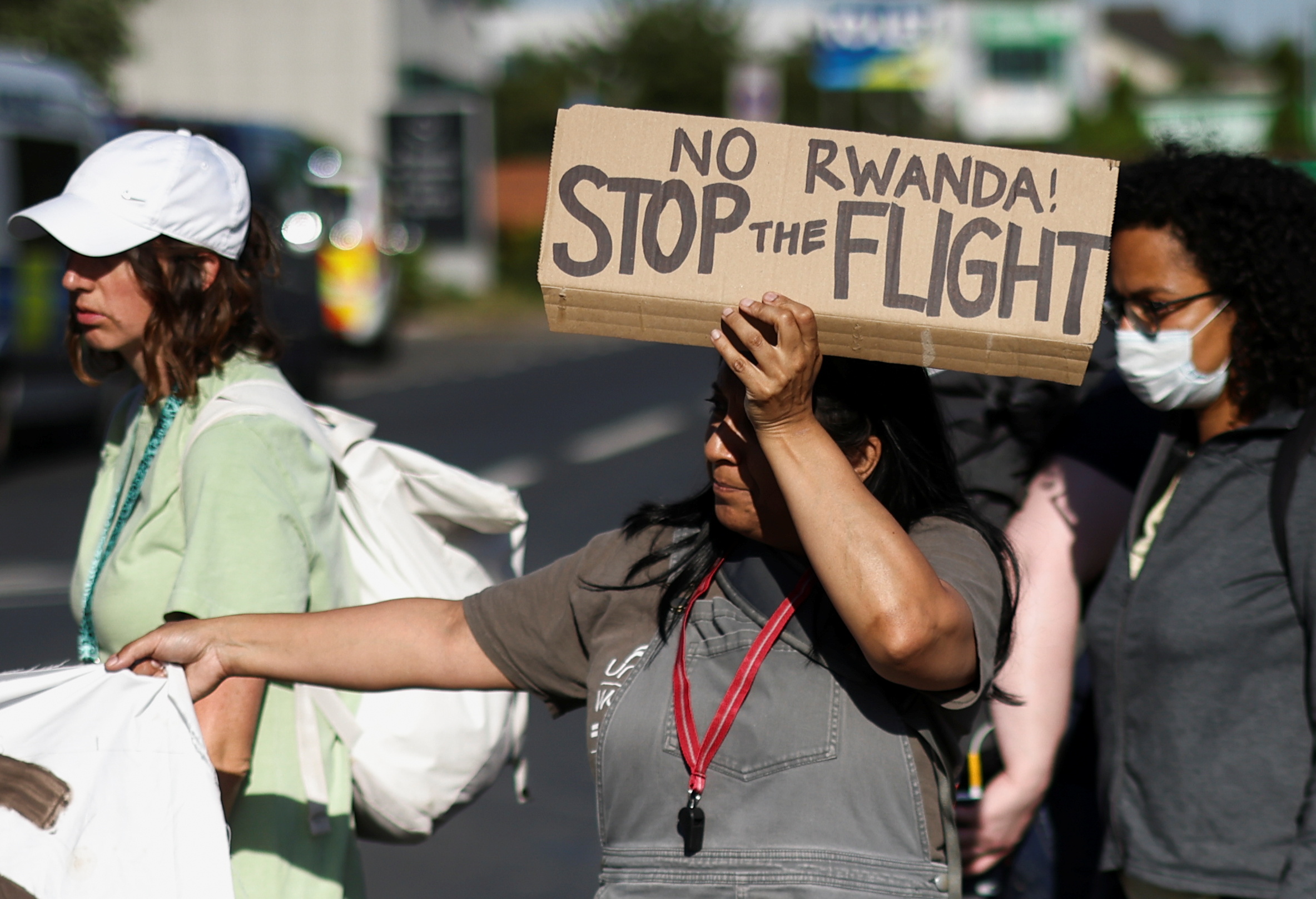 An activist blocking a road leading away from the Colnbrook Immigration Removal Centre holds a banner during a protest against the British Governments plans to deport asylum seekers to Rwanda