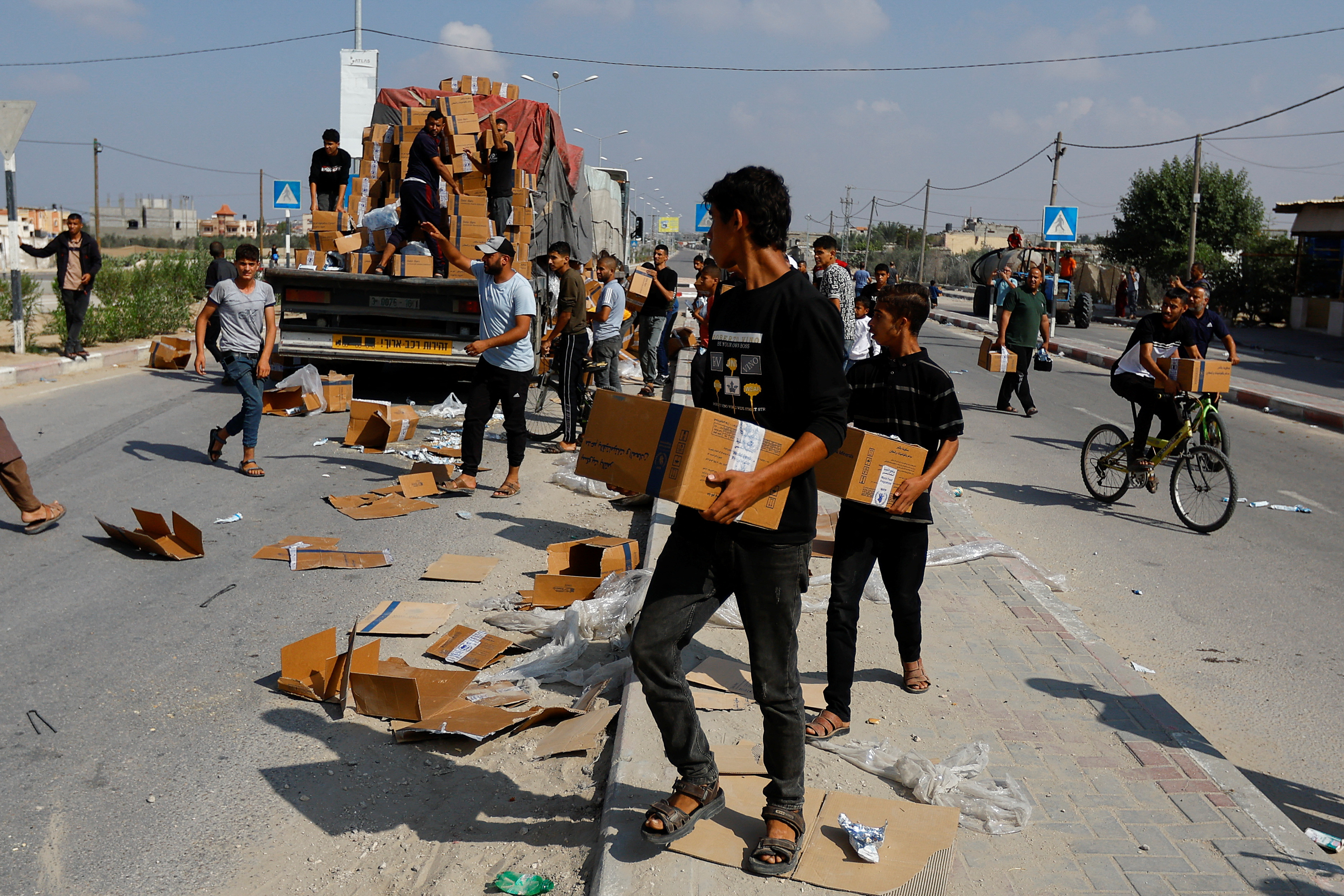 Palestinians carry aid that has fallen from a truck, amid shortages of food supplies in Rafah, southern Gaza Strip