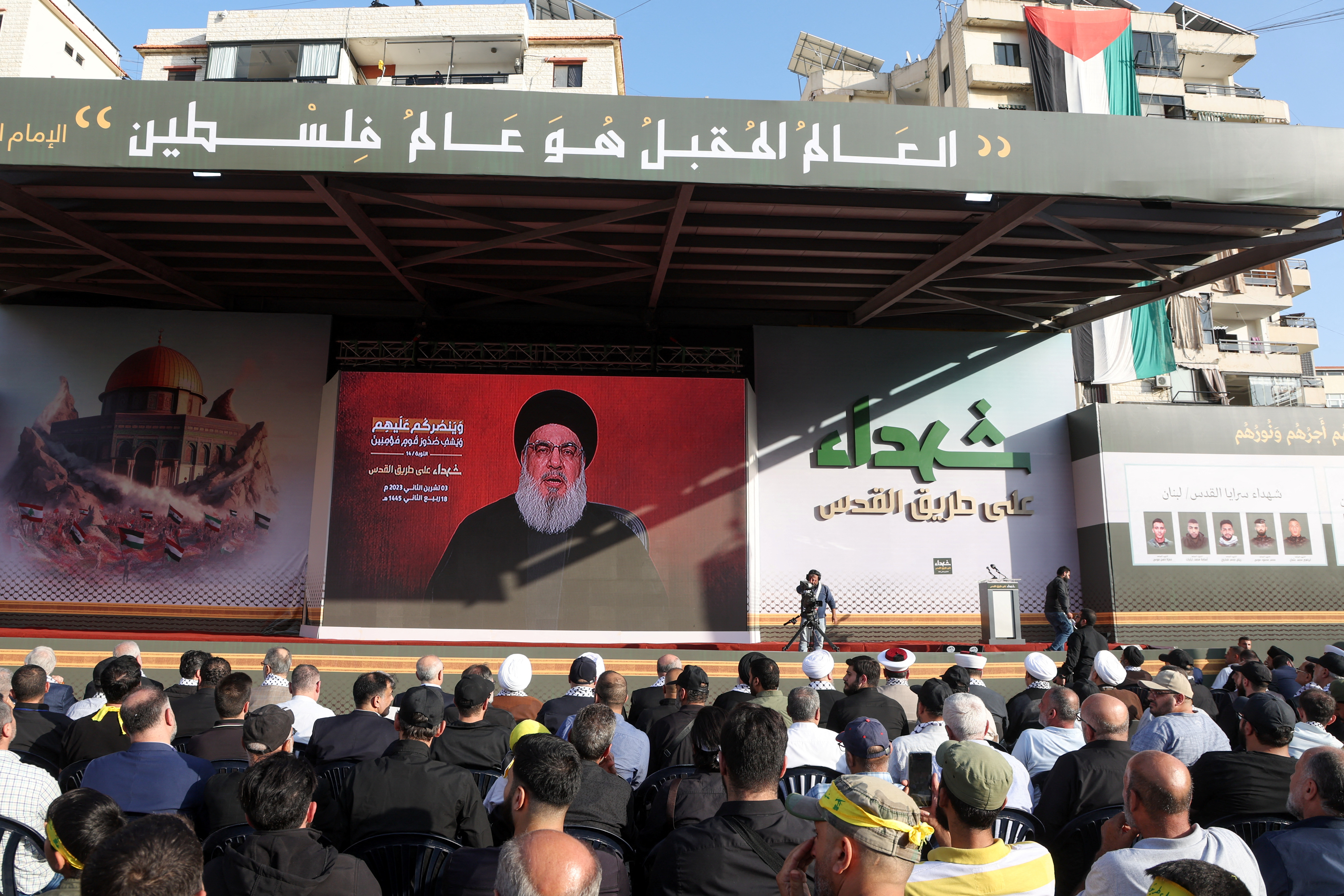 Lebanon's Hezbollah leader Sayyed Hassan Nasrallah appears on a screen as he addresses his supporters during a ceremony to honour fighters killed in the recent escalation with Israel