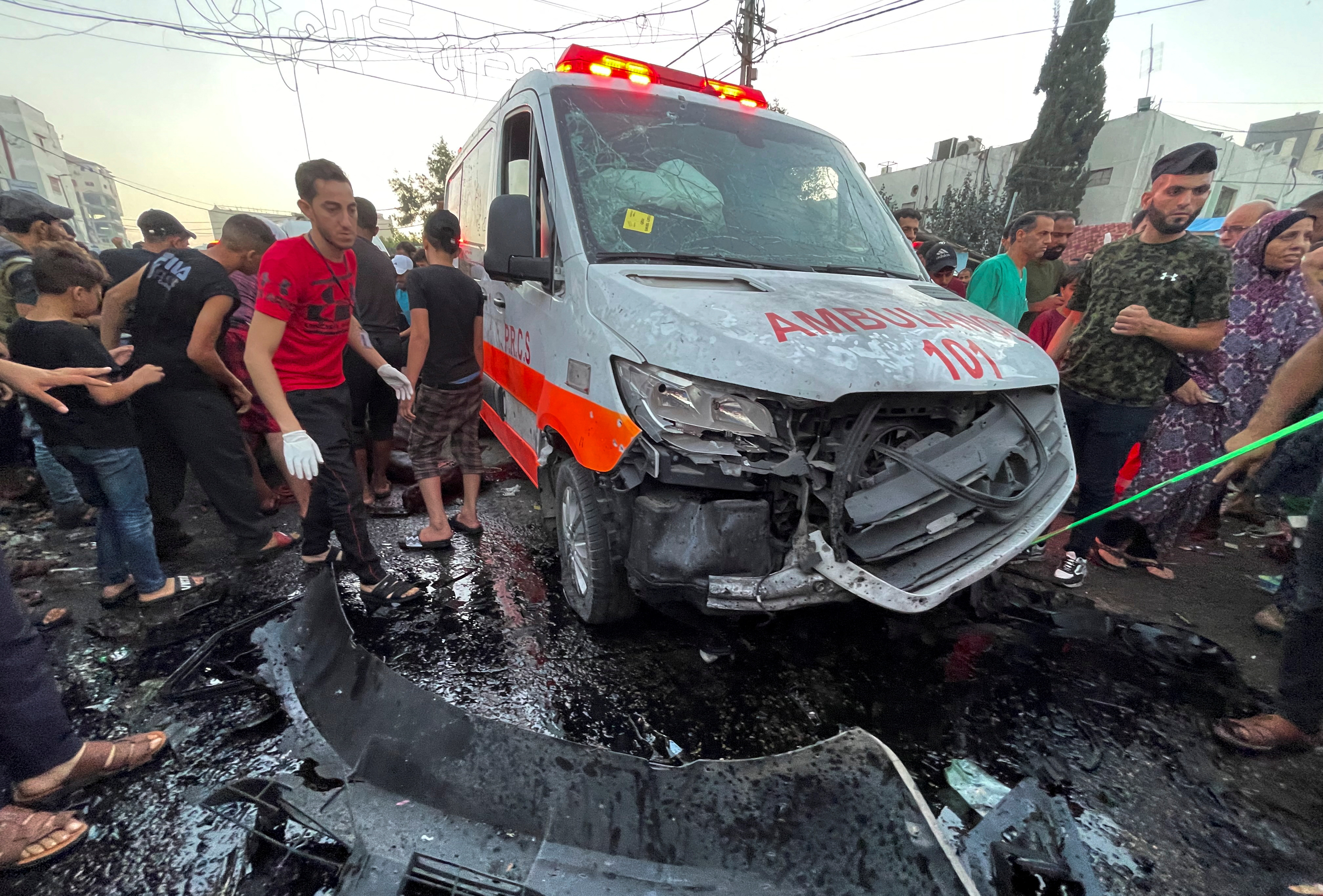 Palestinians check the damages after a convoy of ambulances was hit