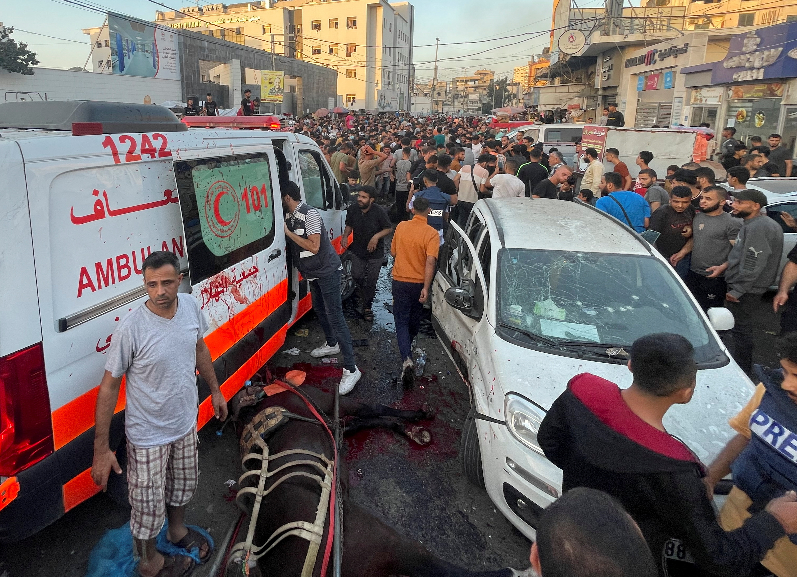 Palestinians check the damages after a convoy of ambulances was hit, at the entrance of Shifa hospital in Gaza City